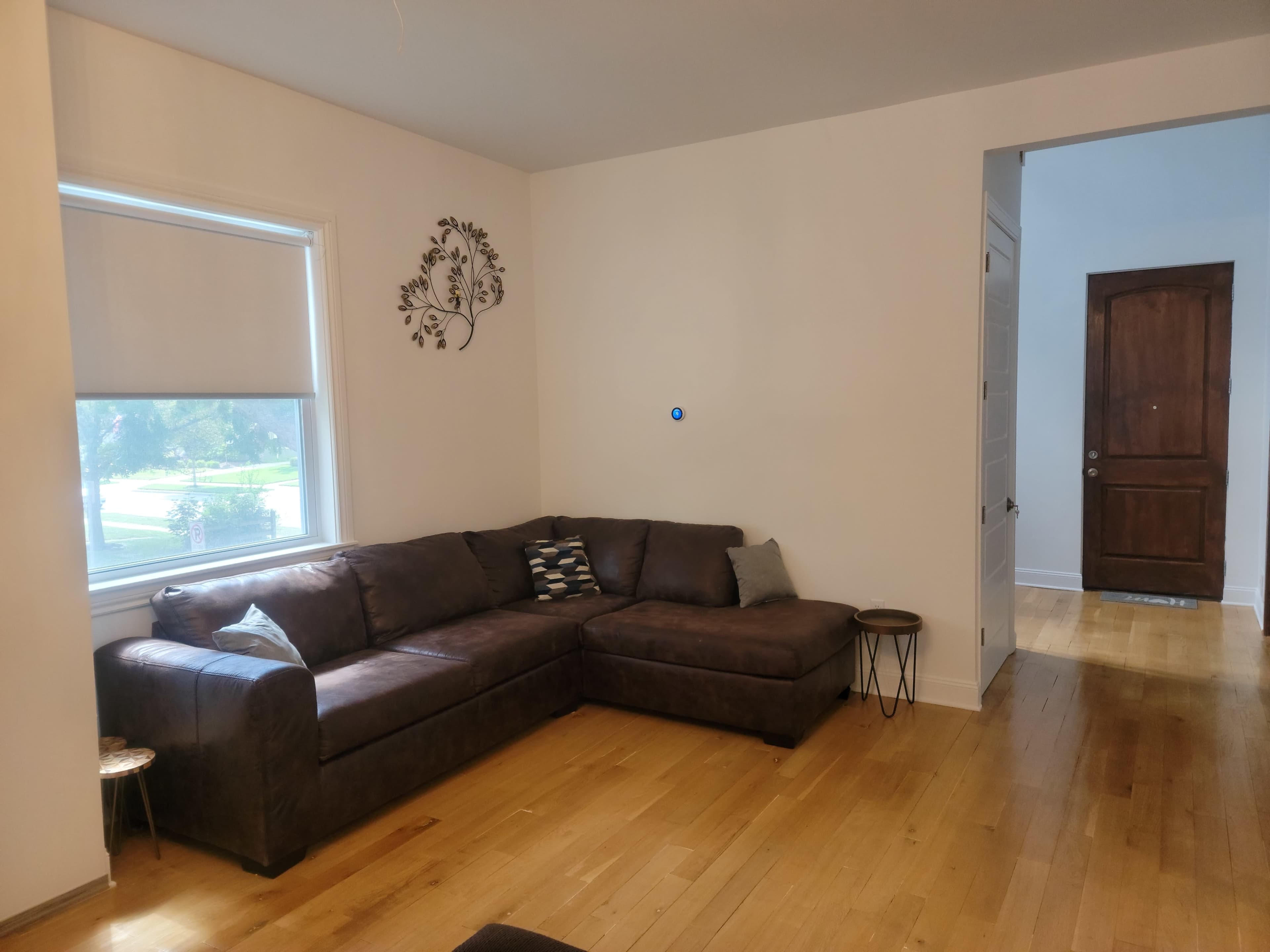 A living room featuring a brown sectional couch, a small side table, and a door leading to another room.
