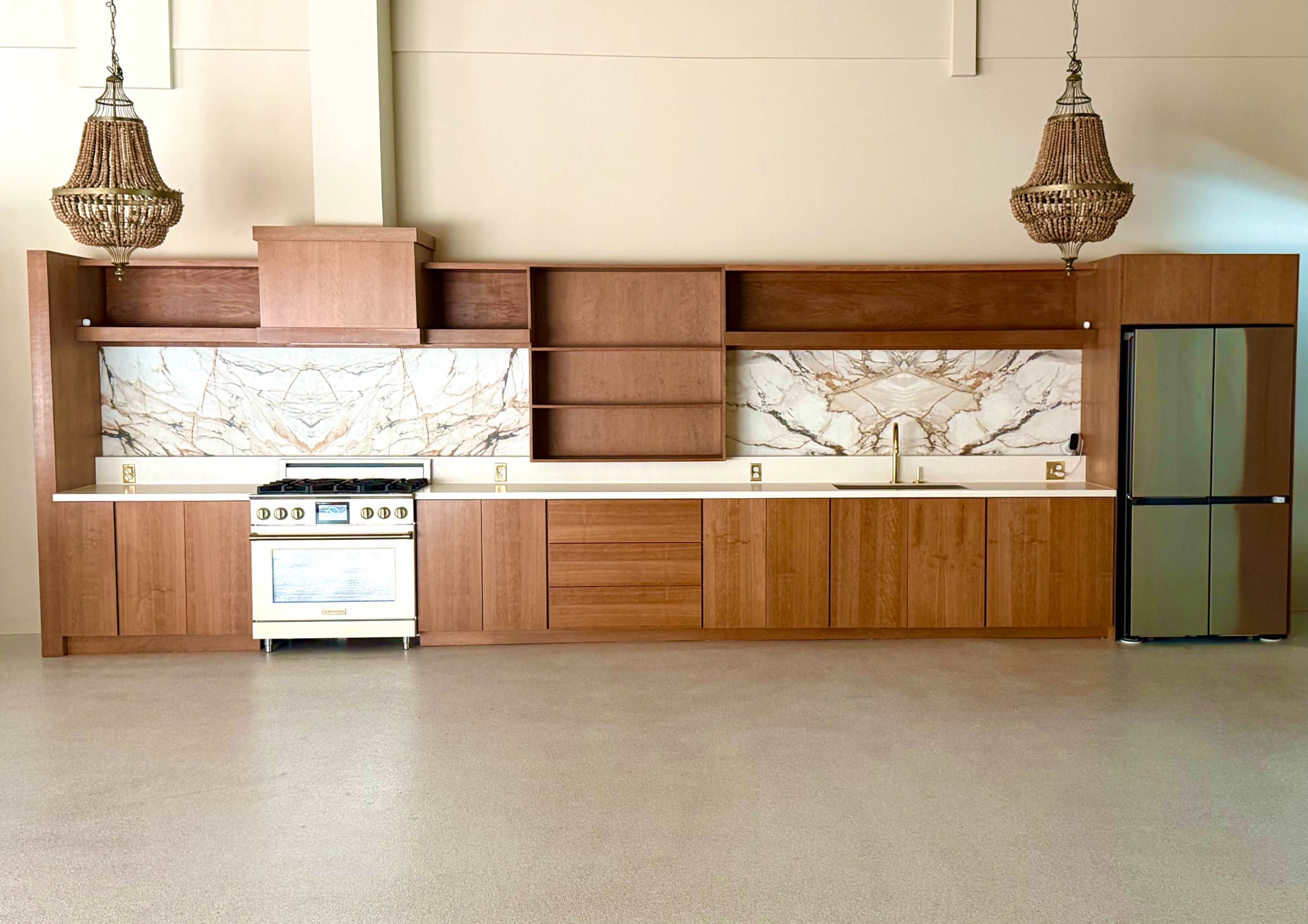 A modern kitchen features a minimalist design with wooden cabinets, a white countertop, a gas stove, and marble backsplash.