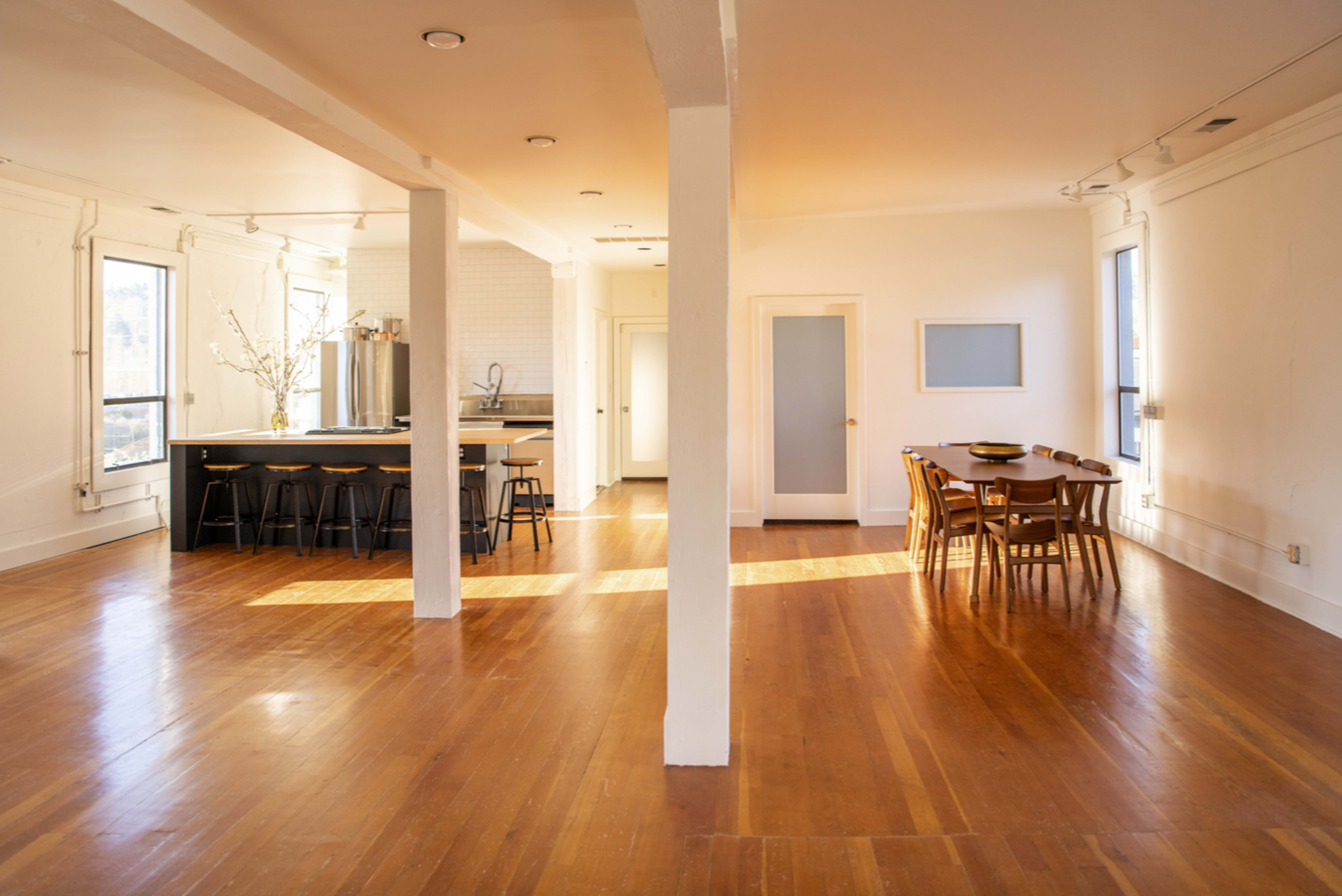 An open-concept living space featuring a kitchen area with a large island and a dining table surrounded by chairs, all on hardwood flooring.