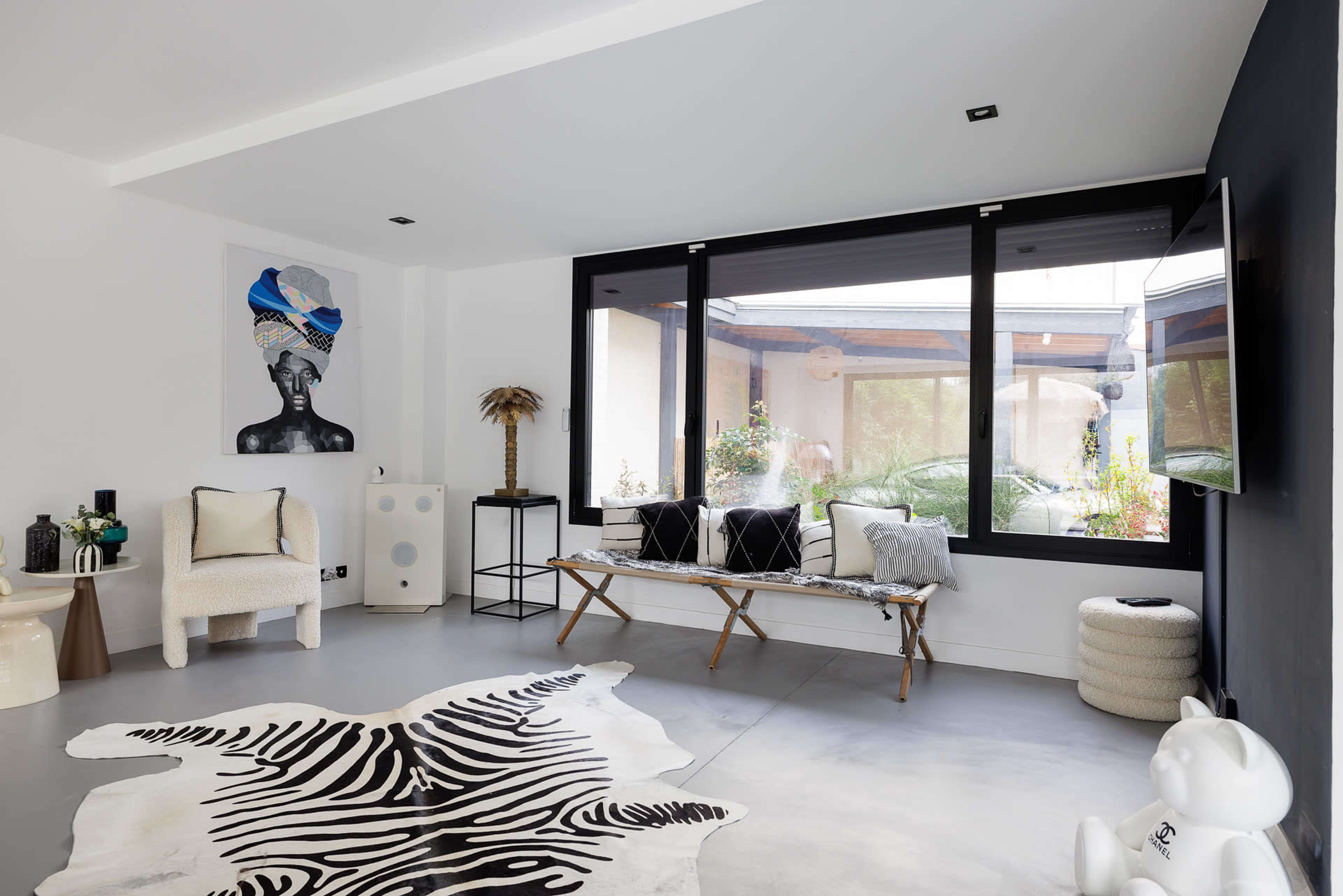 A modern living room featuring a black and white color scheme, a large window with outdoor views, and a combination of contemporary furniture and décor.