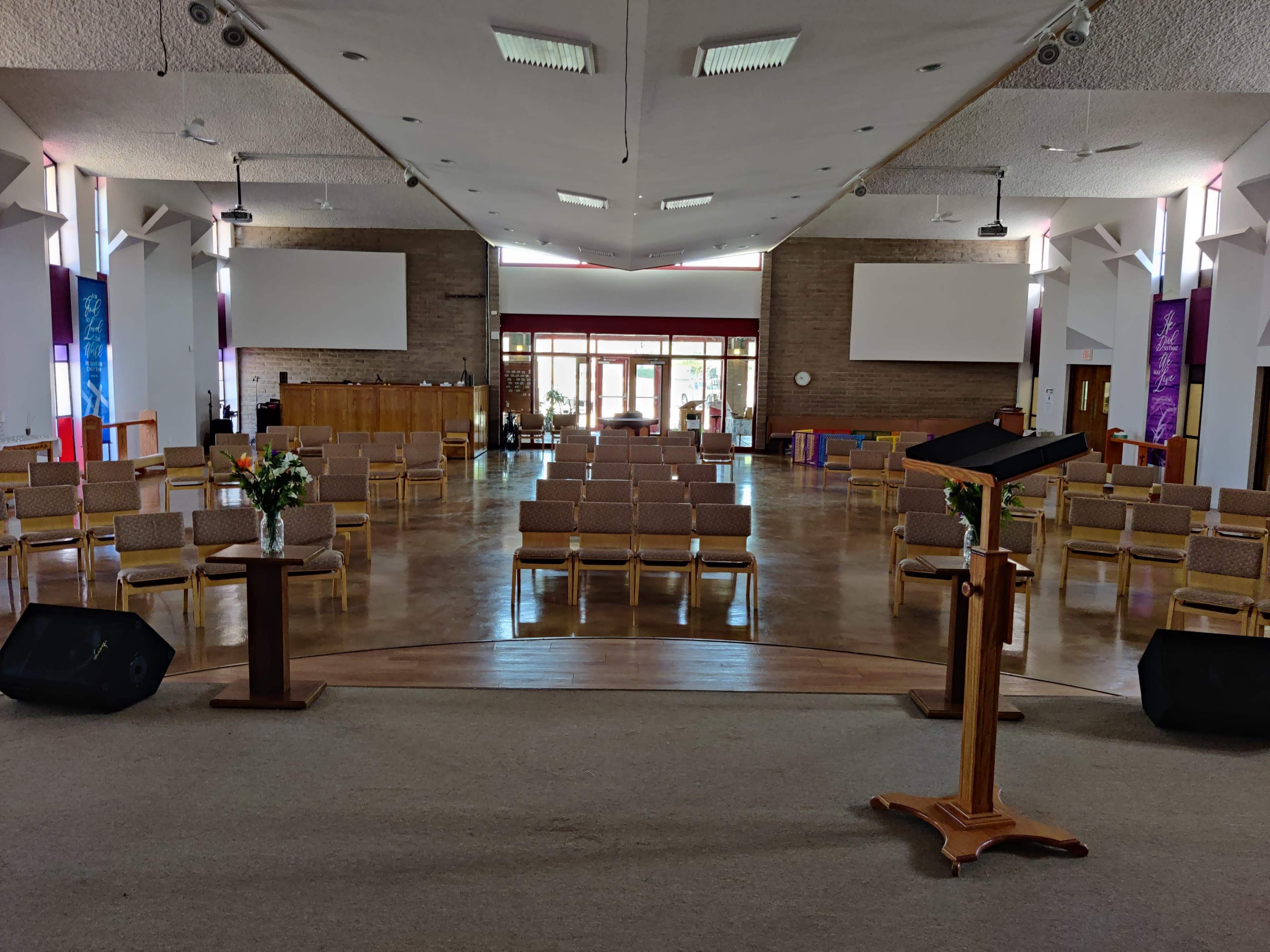 A spacious interior of a church with rows of chairs arranged facing a podium at the front.