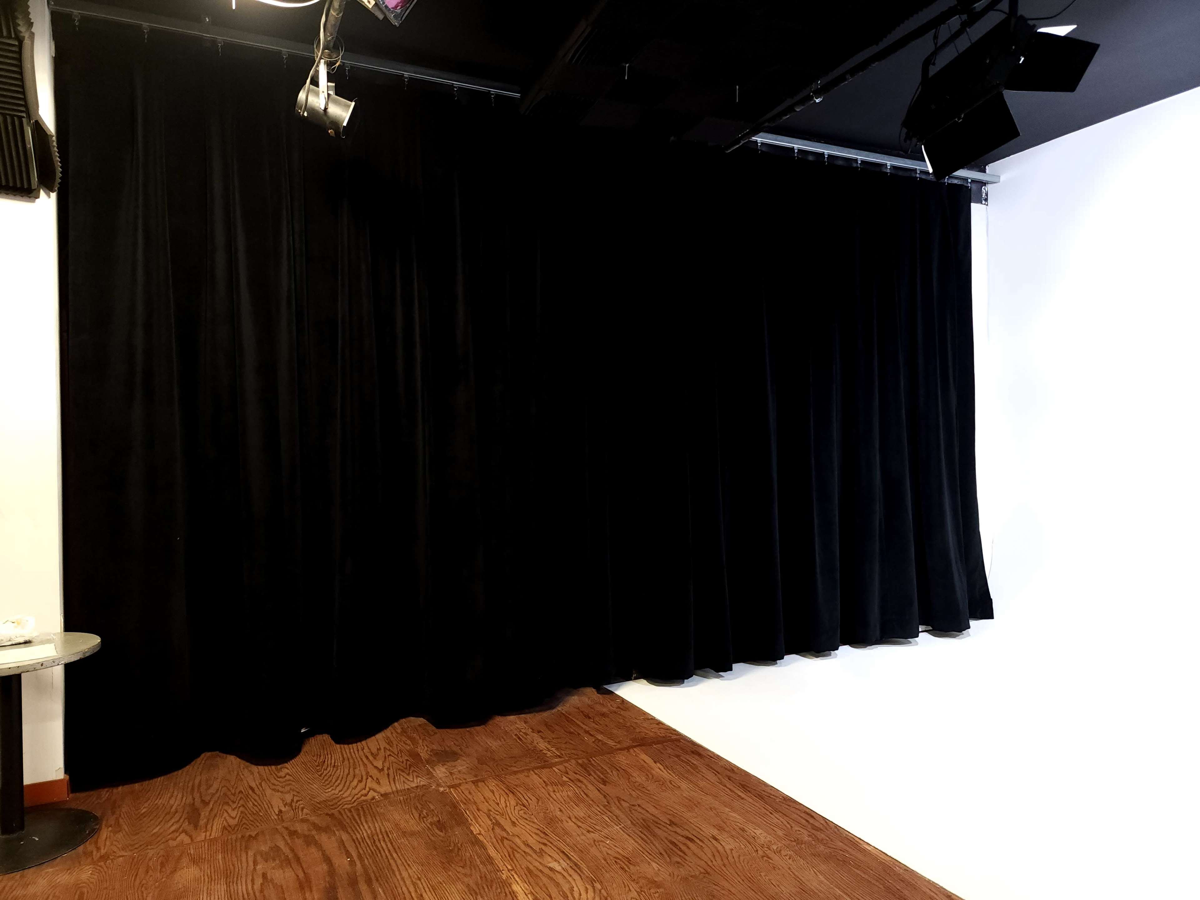 A black velvet curtain is draped across a wall in a room with wooden flooring.