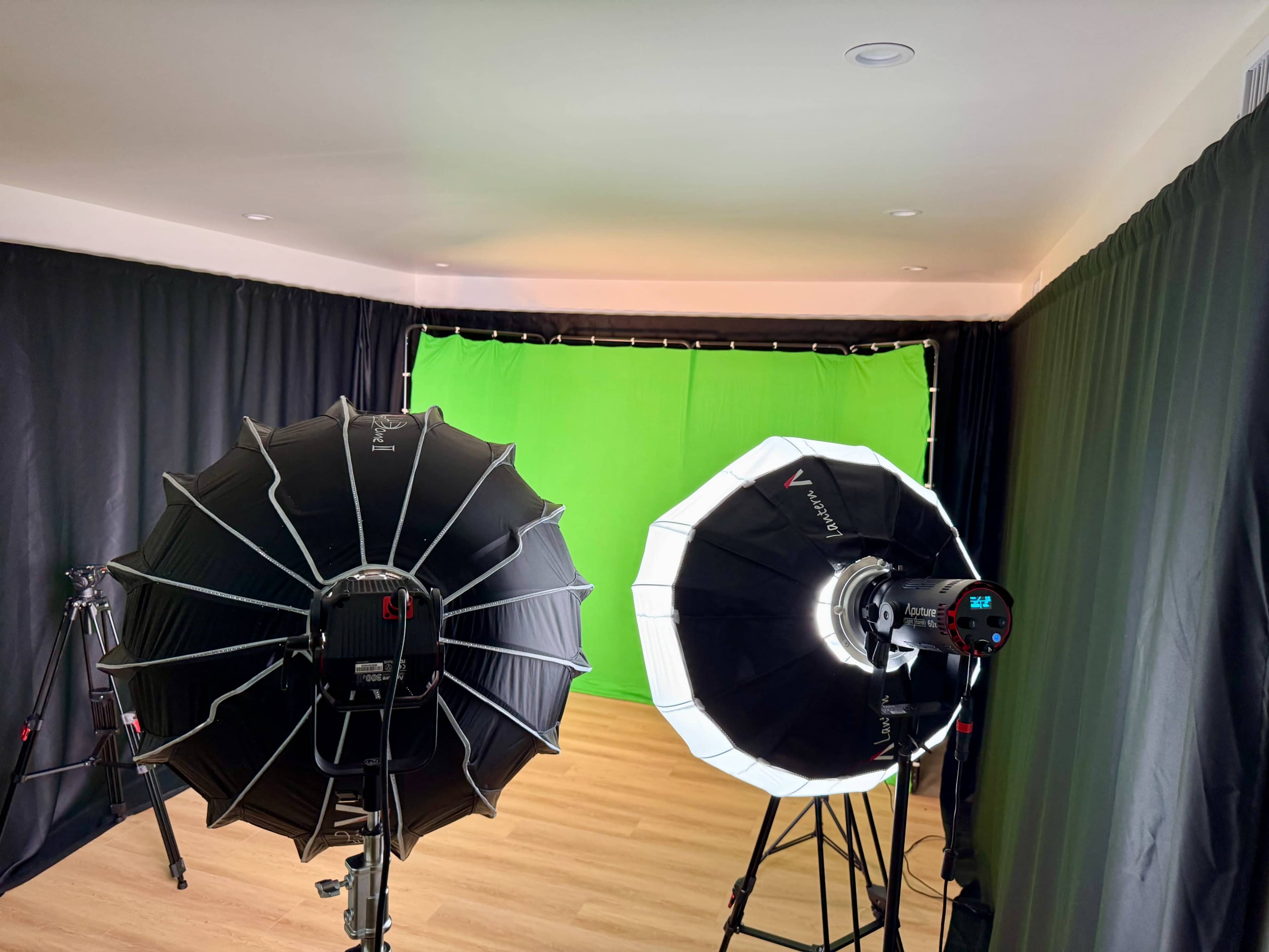 The image shows a photography studio setup with two light sources and a green screen backdrop.