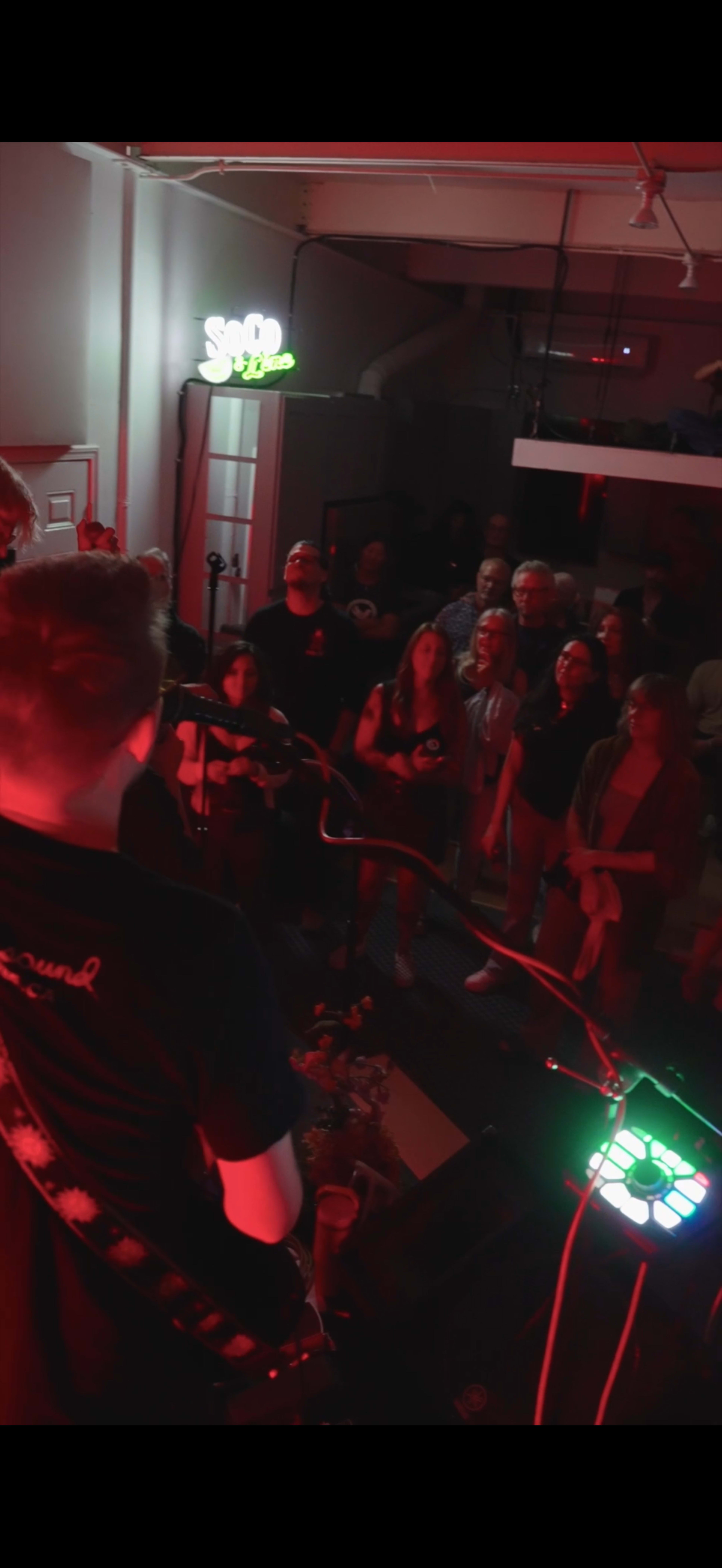 A band performs on stage while a crowd of people watches intently from below.