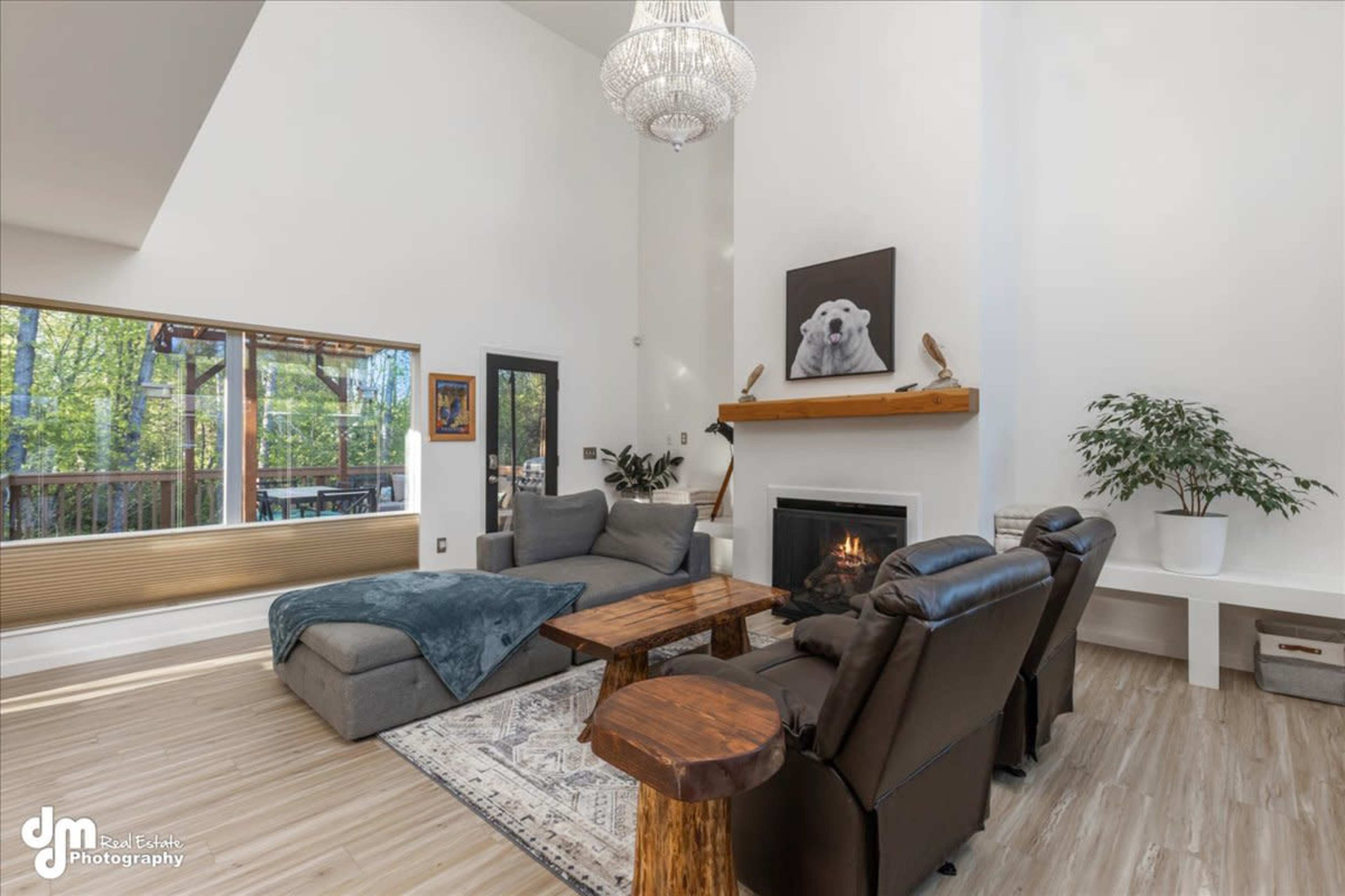 The living room features a large sectional sofa, two recliners, a wooden coffee table, a fireplace, and a high ceiling with a chandelier.