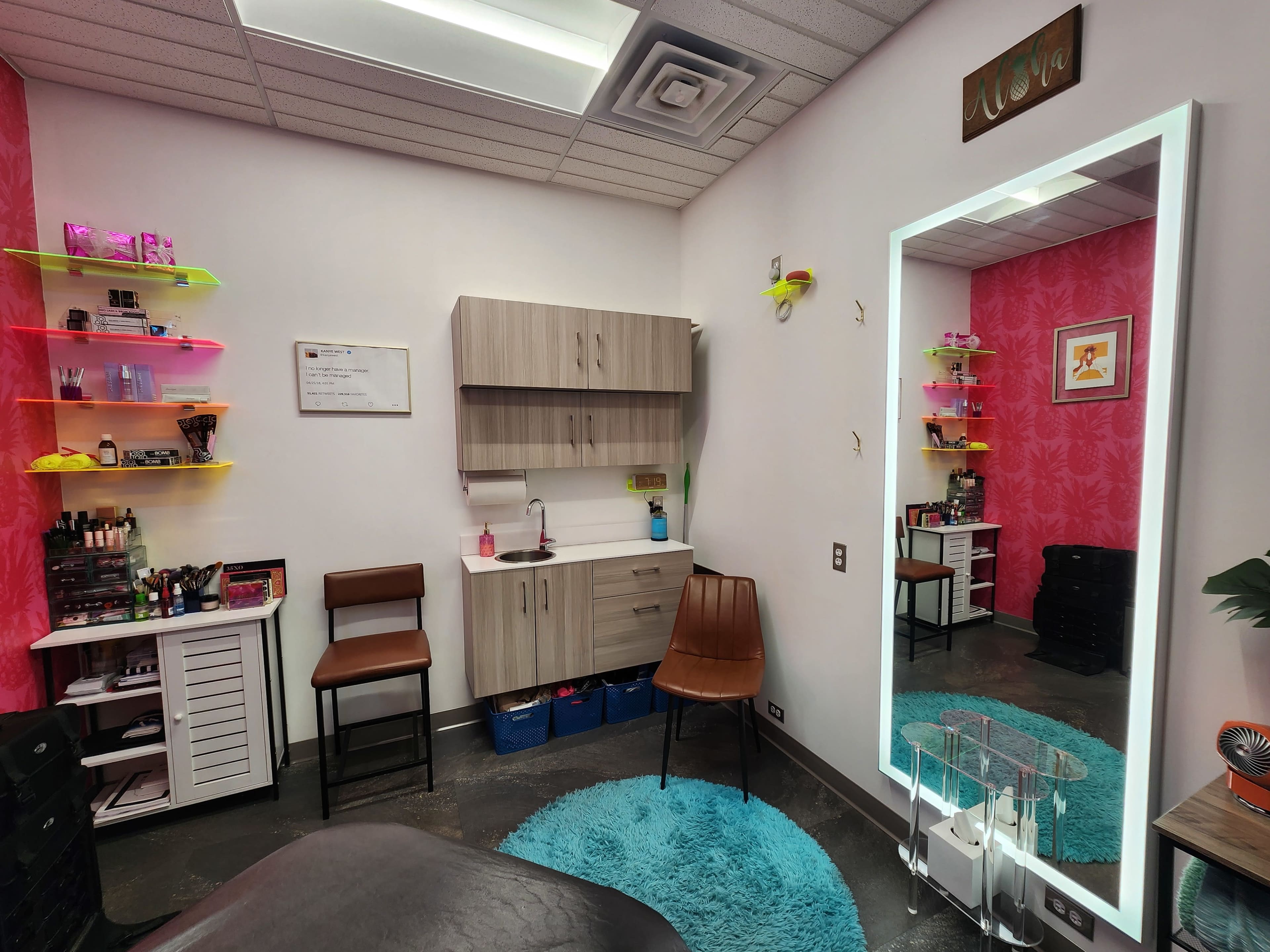 The image shows a small beauty salon room with pink walls, shelves displaying beauty products, a chair, and a large mirror.