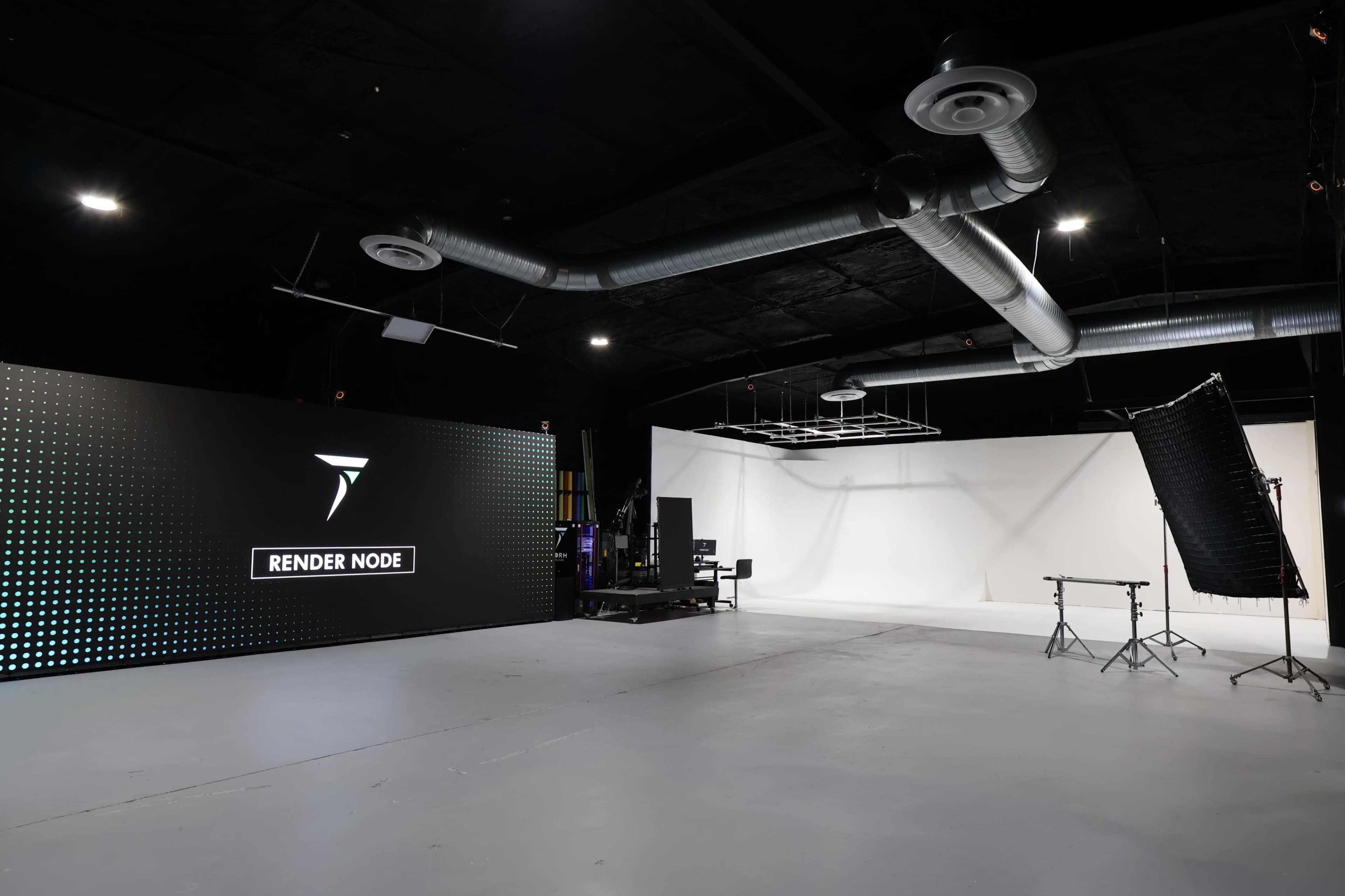 The image shows an empty studio space equipped with a large digital display and a blank white backdrop.