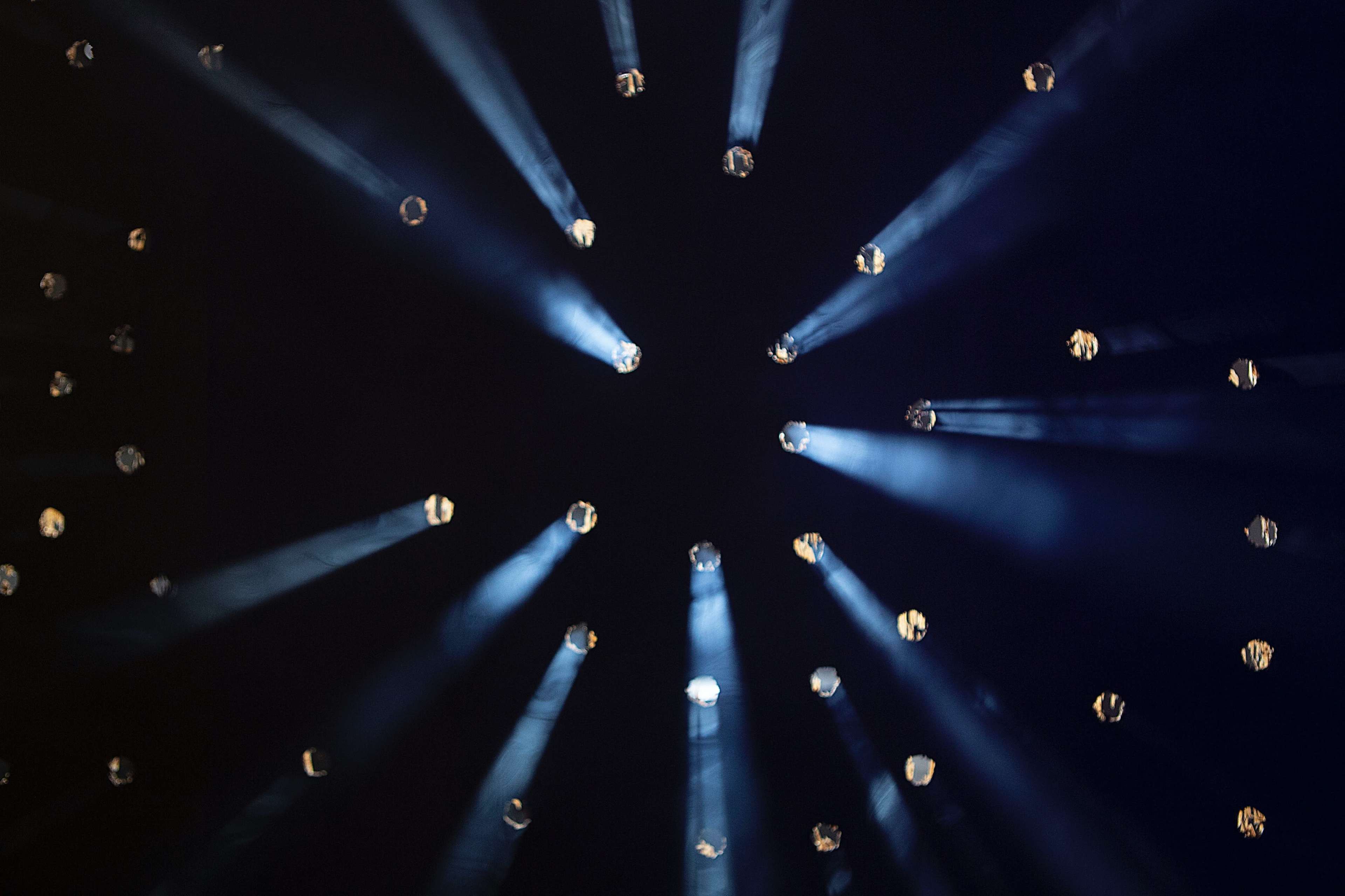 Light beams radiate from various points against a dark background, creating a star-like effect.