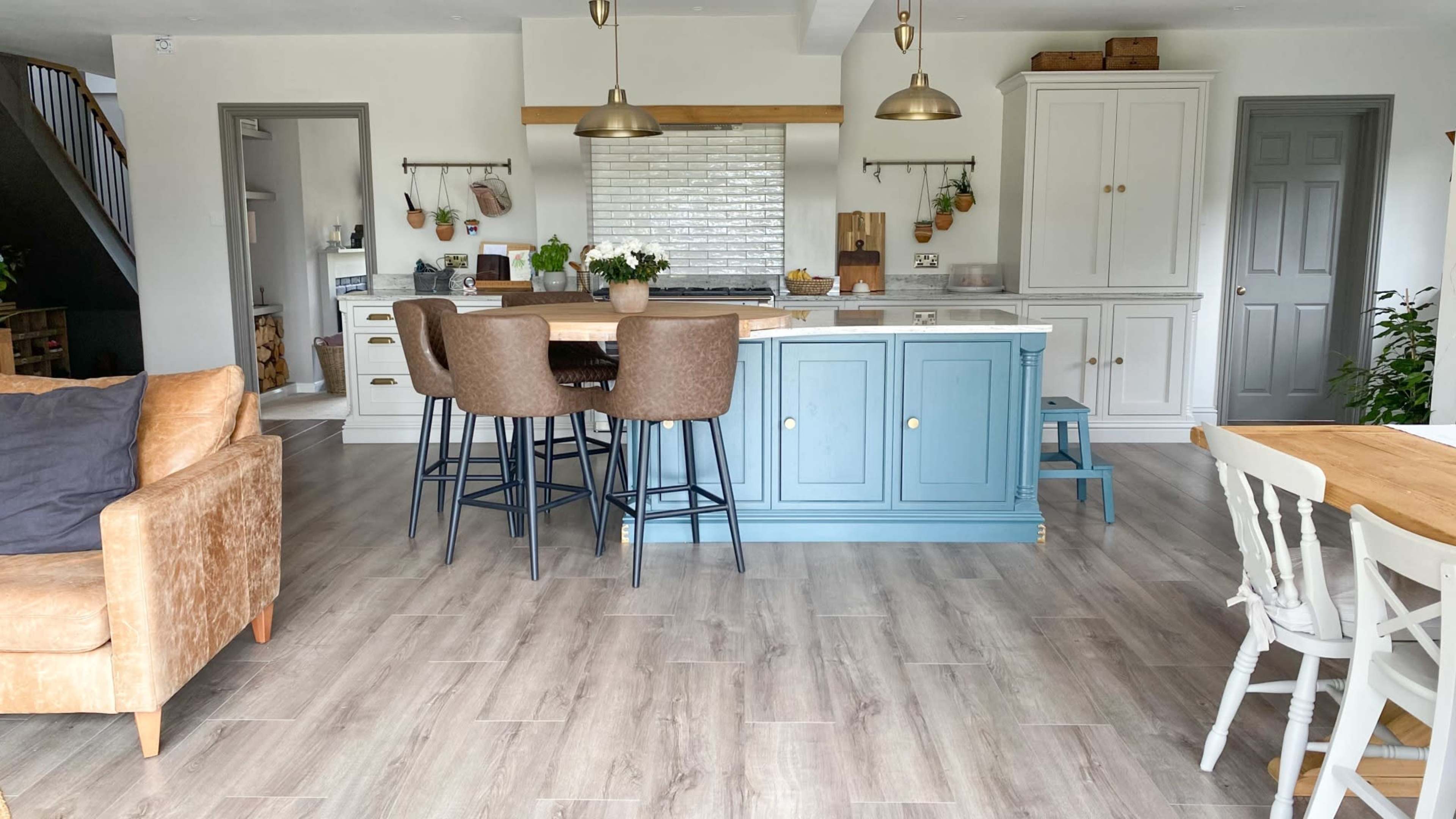 A modern kitchen and dining area with an island, bar stools, and a mix of wooden and light-colored cabinetry.