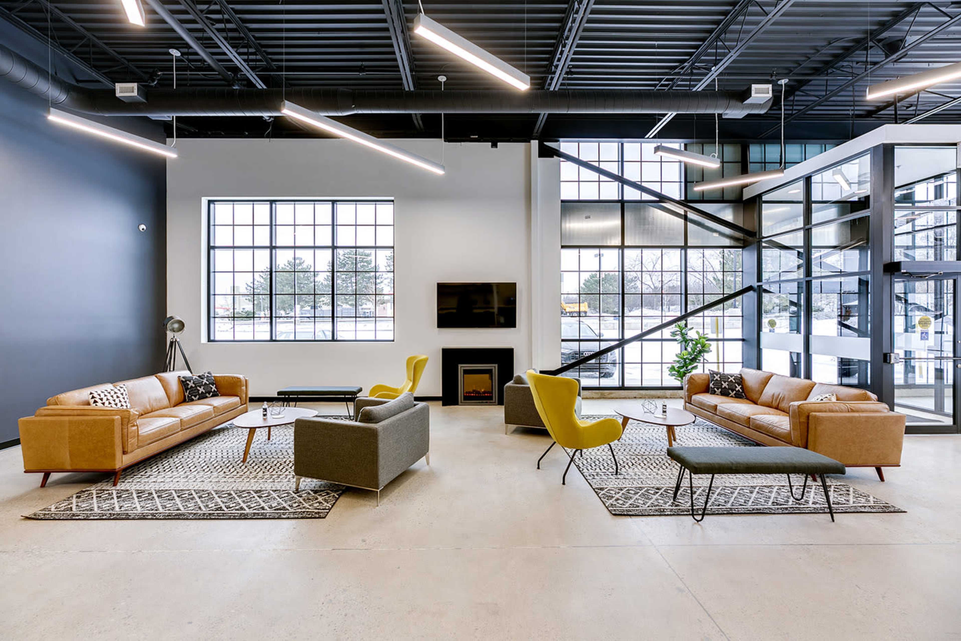 A modern indoor lounge area featuring multiple sofas, coffee tables, and large windows that provide ample natural light.