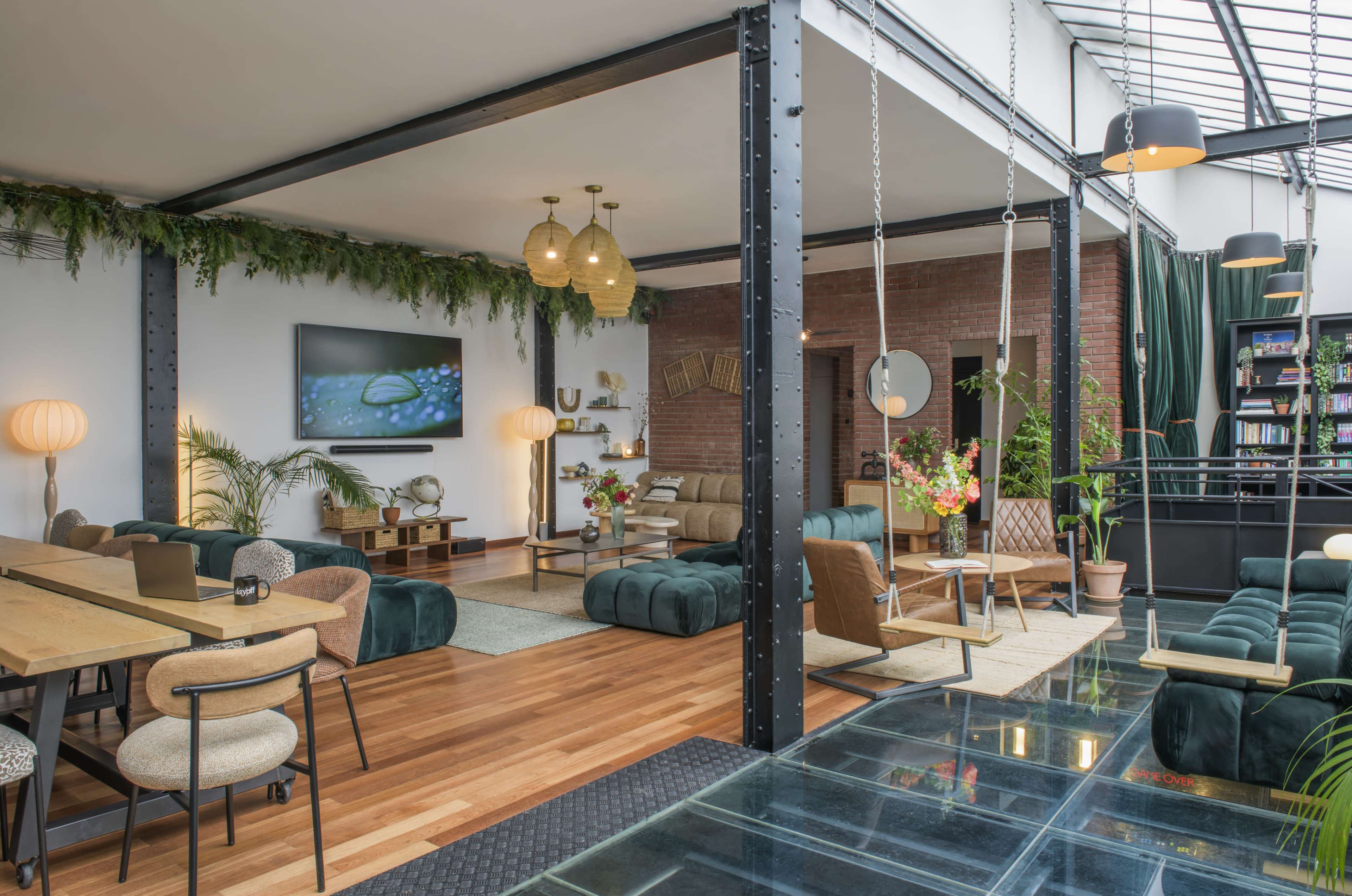 The image features a modern open-concept living space with a combination of seating areas, greenery, and a glass floor accent.