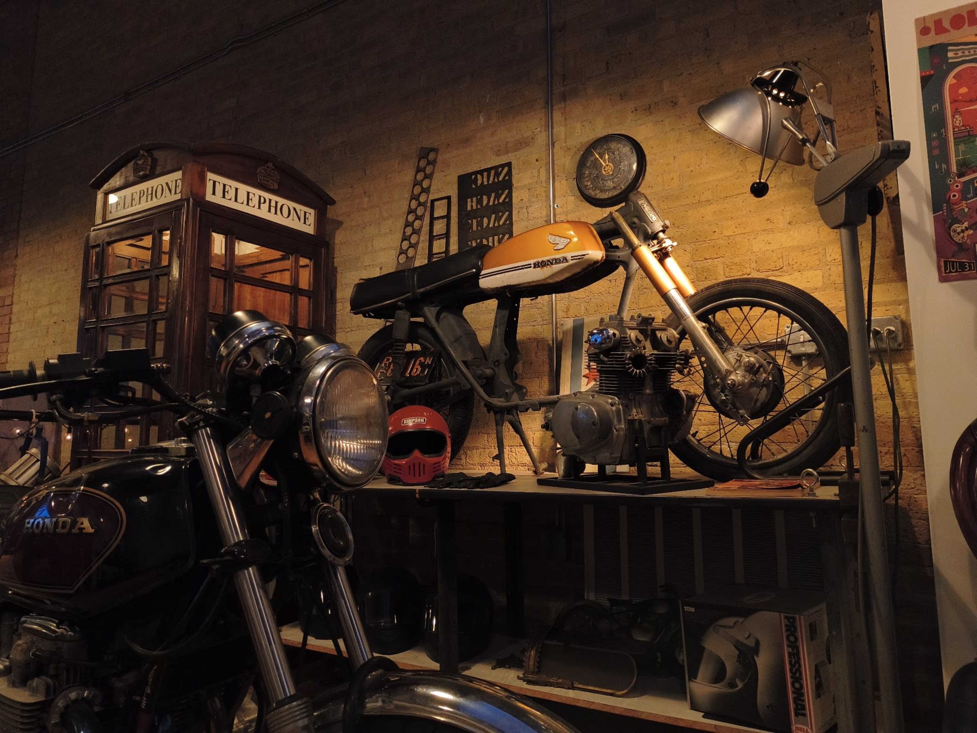 A vintage motorcycle is displayed on a shelf alongside a classic telephone booth and various memorabilia.