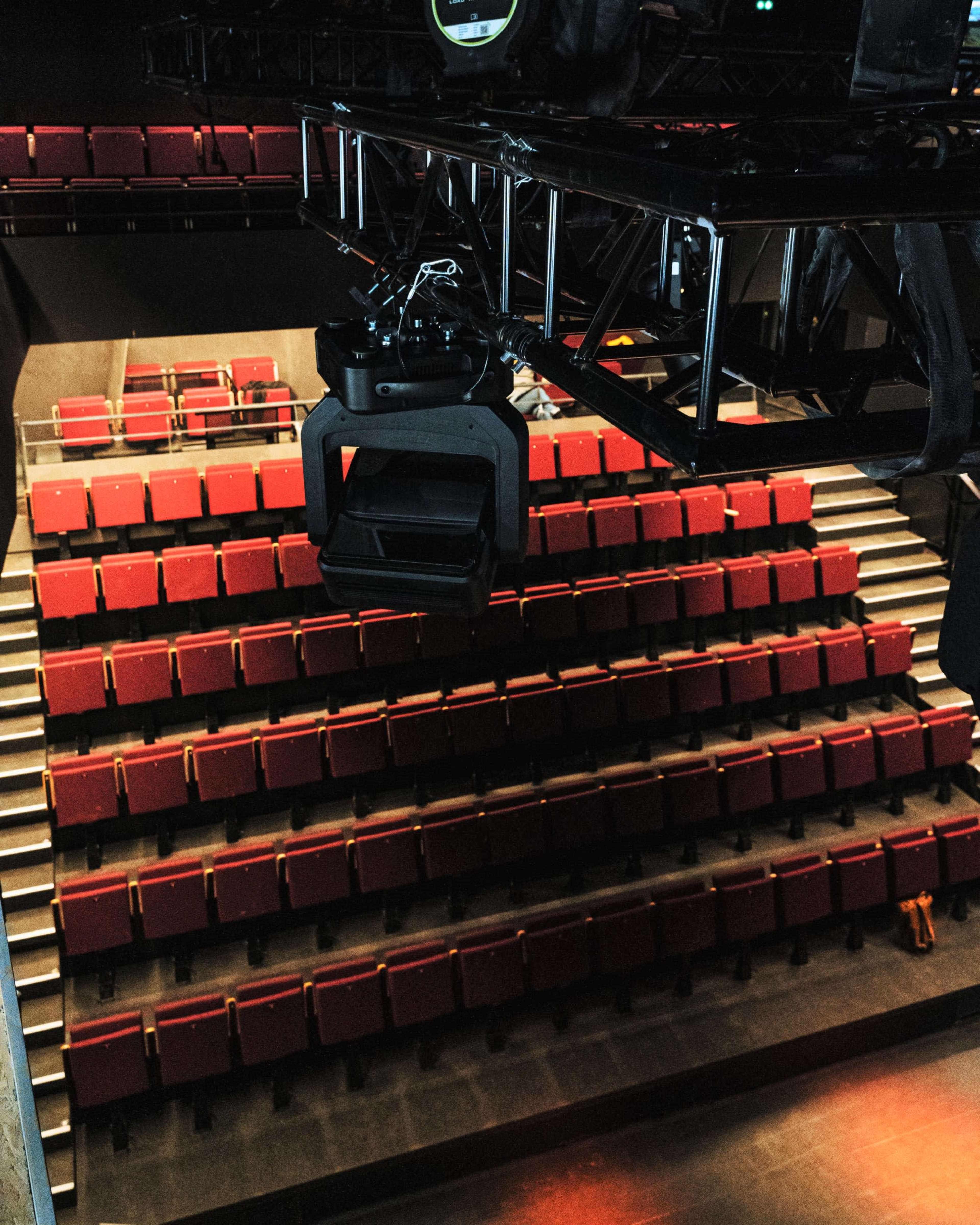 A theater auditorium with empty red seats arranged in several rows.