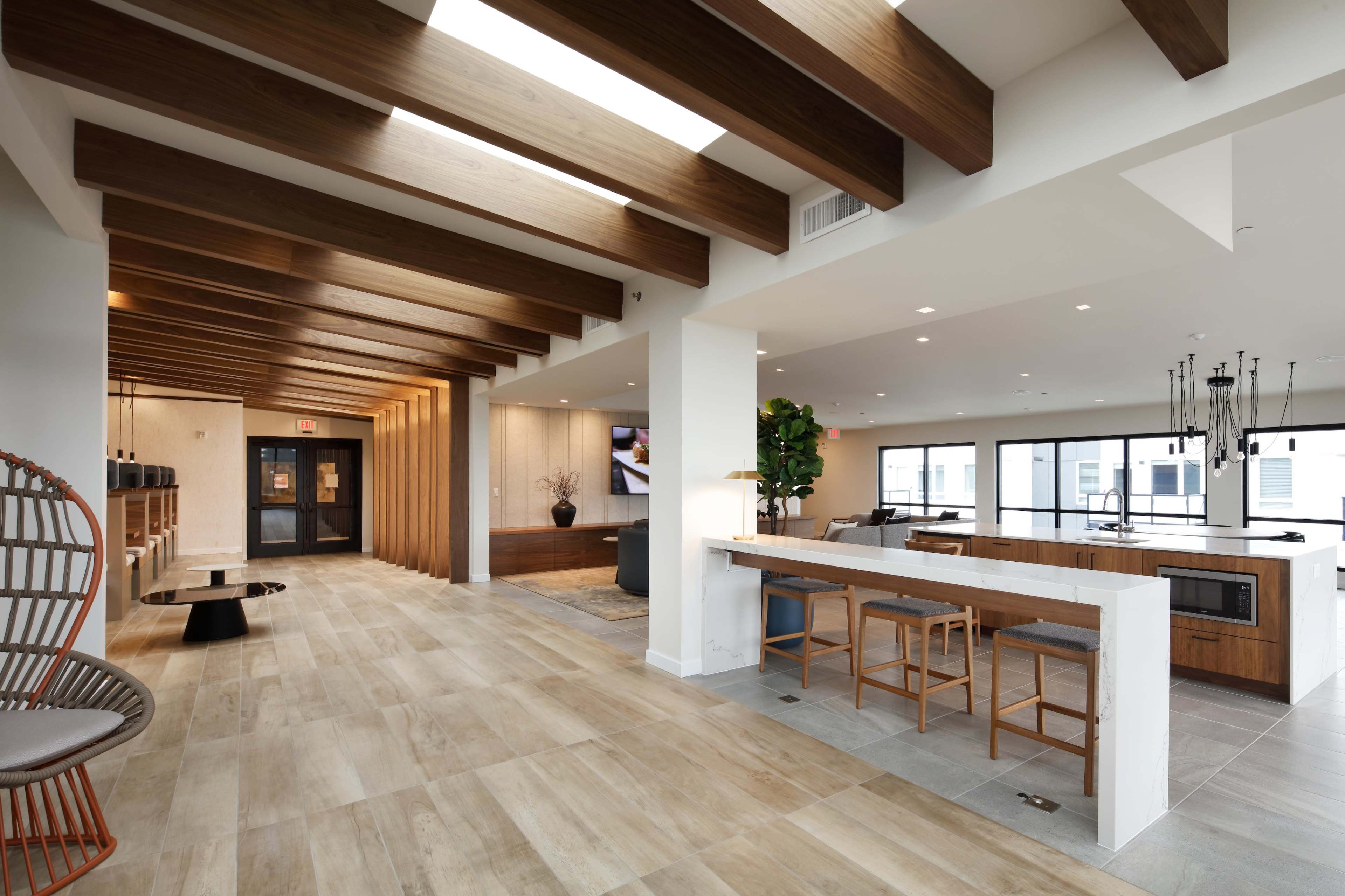 A modern, open interior space featuring wooden beams, a kitchen area, and a seating area with contemporary furniture.