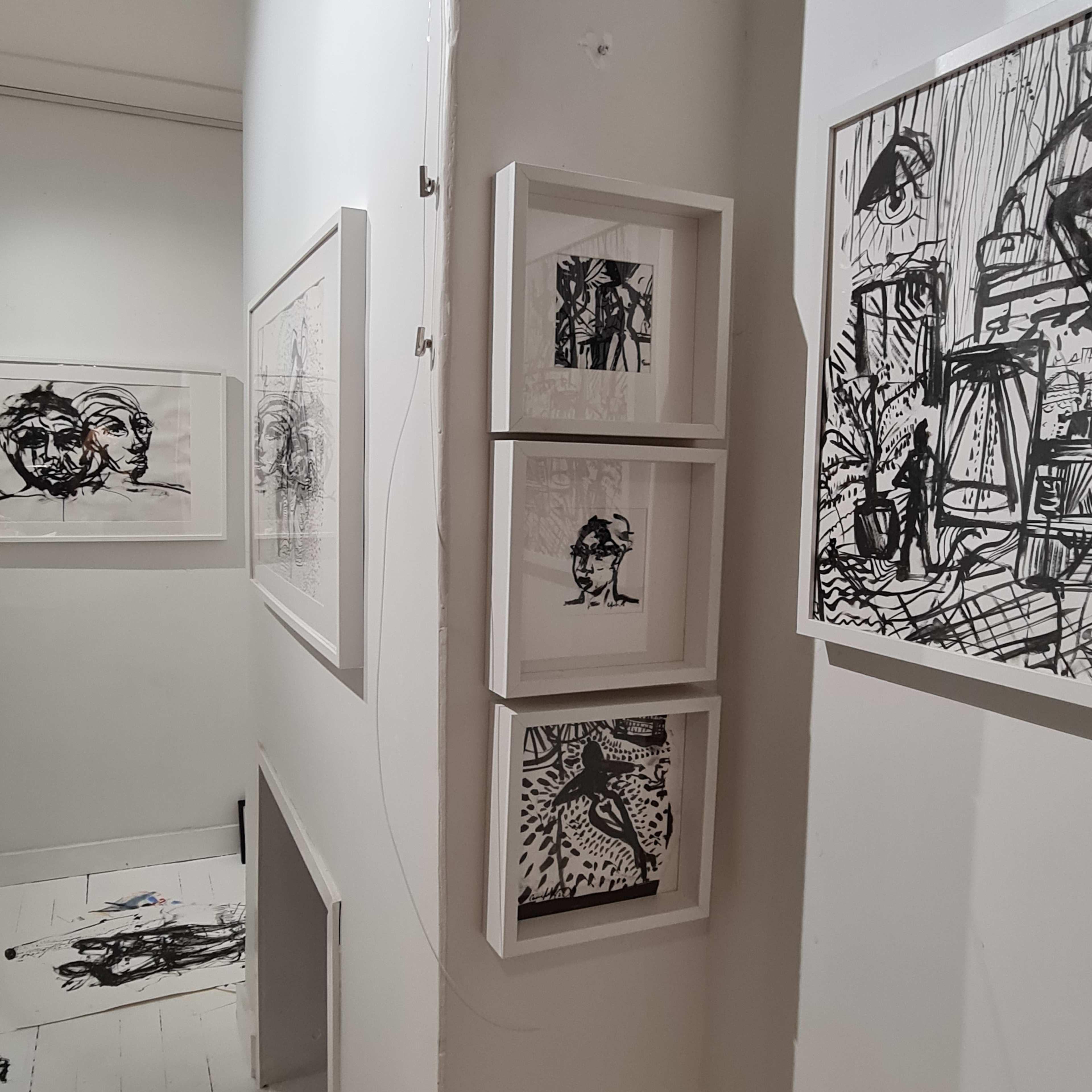 A narrow hallway with black and white framed artworks displayed on the walls, leading to a stairway entrance.