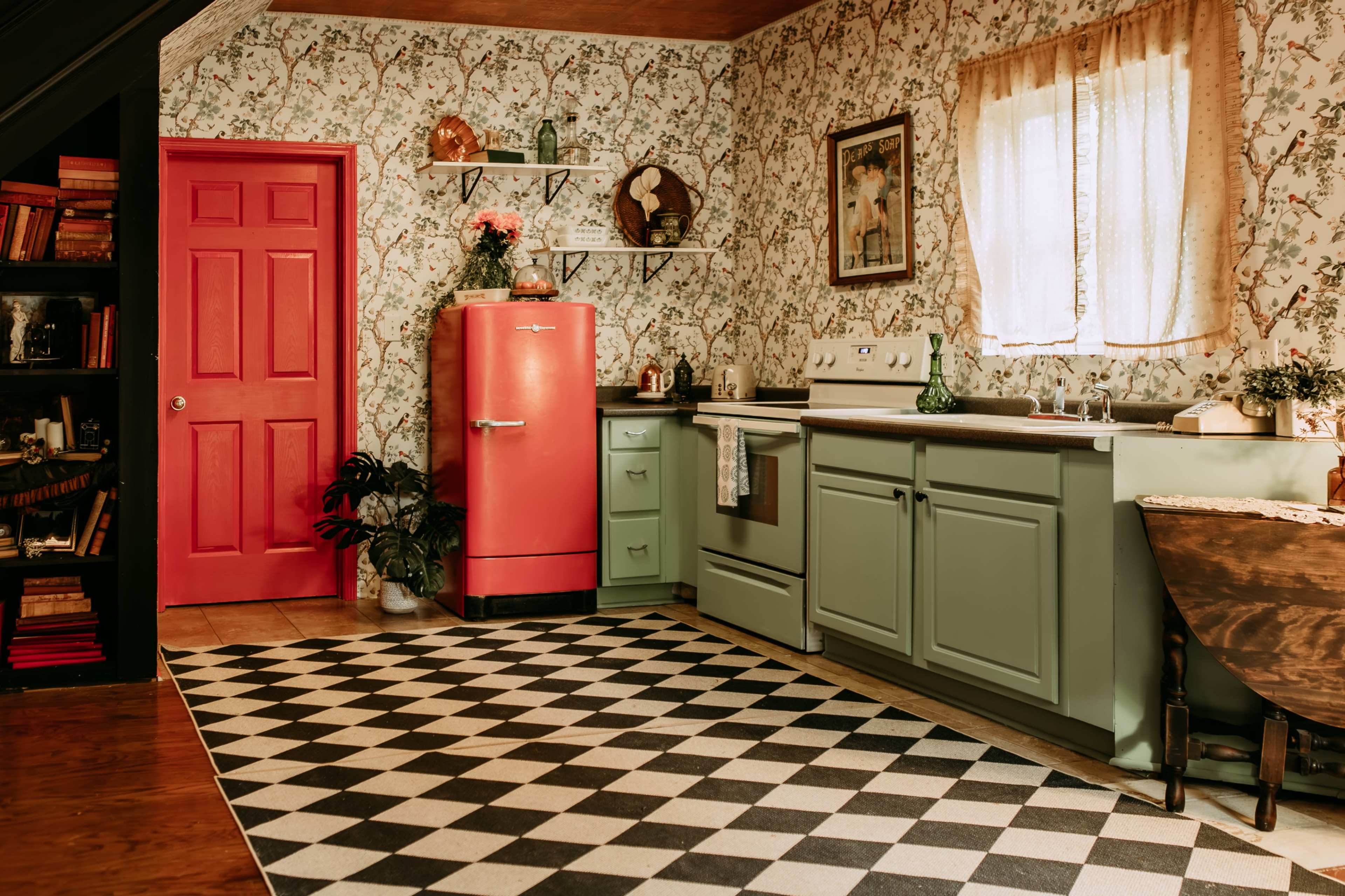 The image shows a vintage kitchen with mint green cabinets, a pink refrigerator, and a checkered black and white floor.