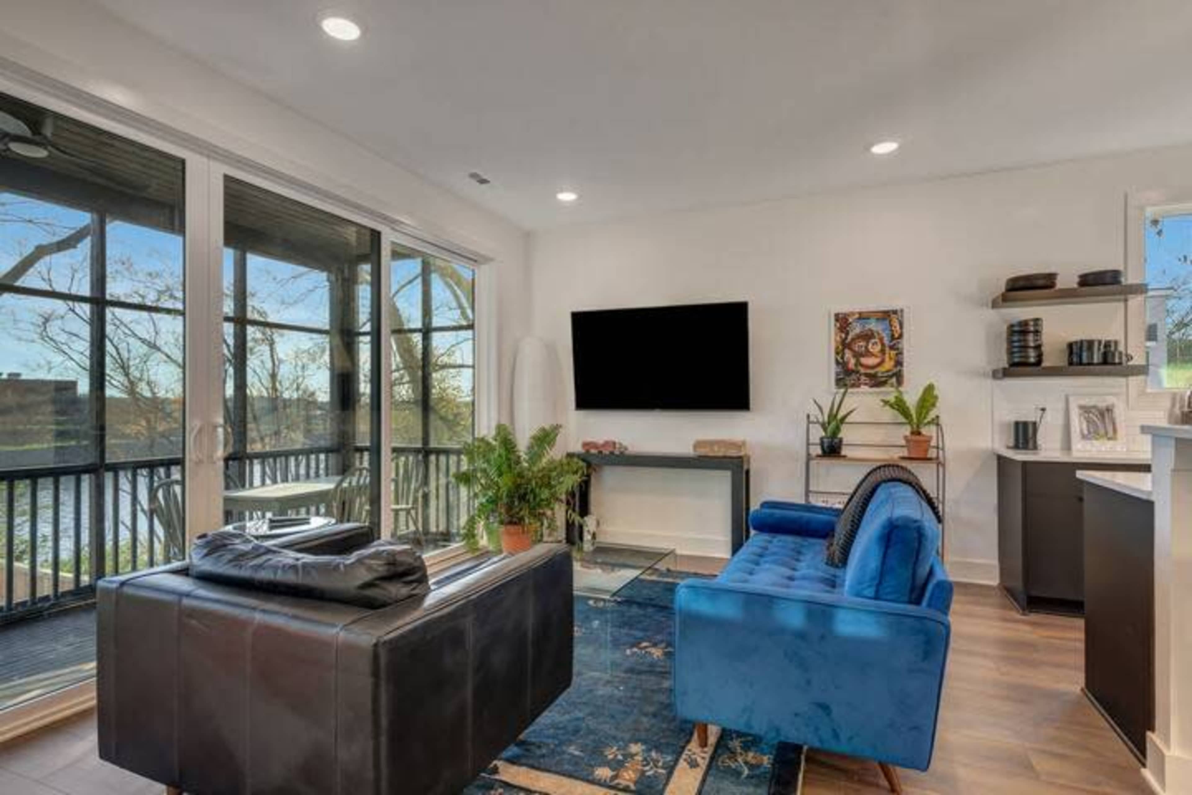 A modern living room features a blue sofa and a coffee table, with large windows overlooking a body of water.