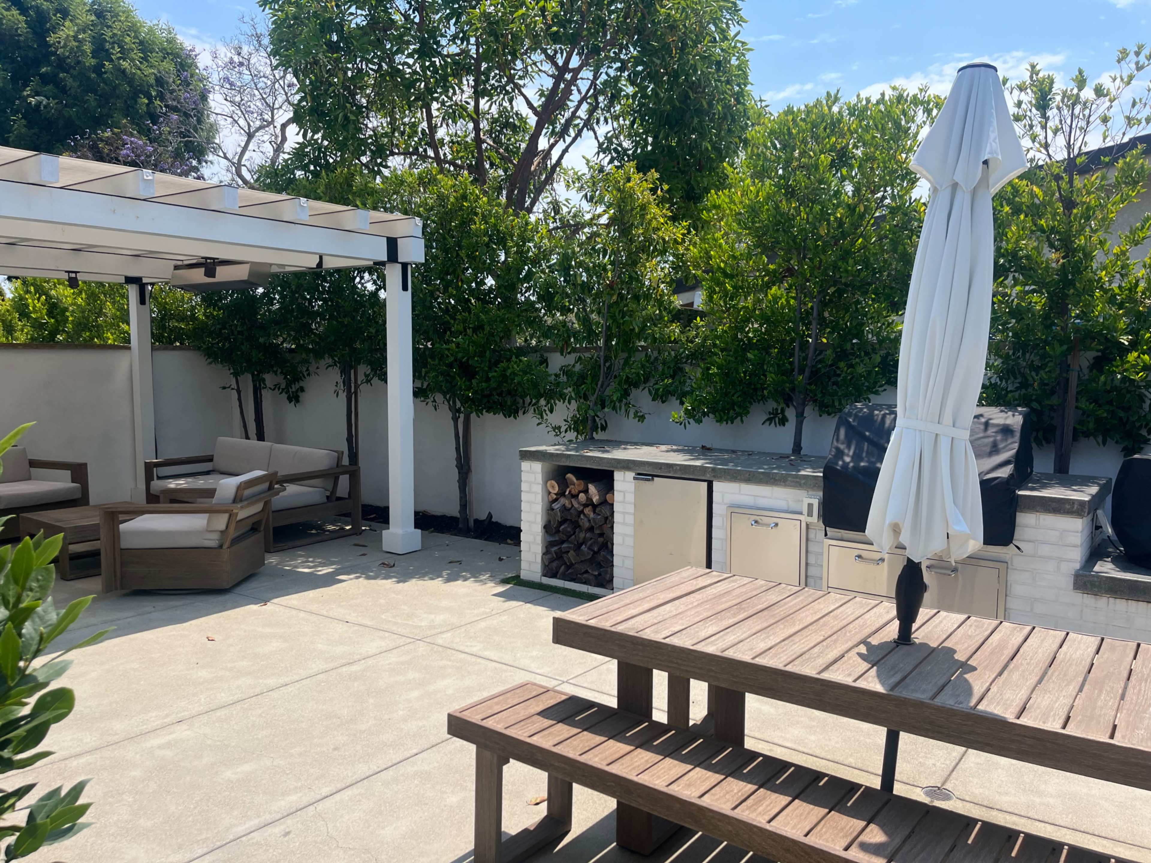A patio area with a seating arrangement, an outdoor kitchen, and a large umbrella.