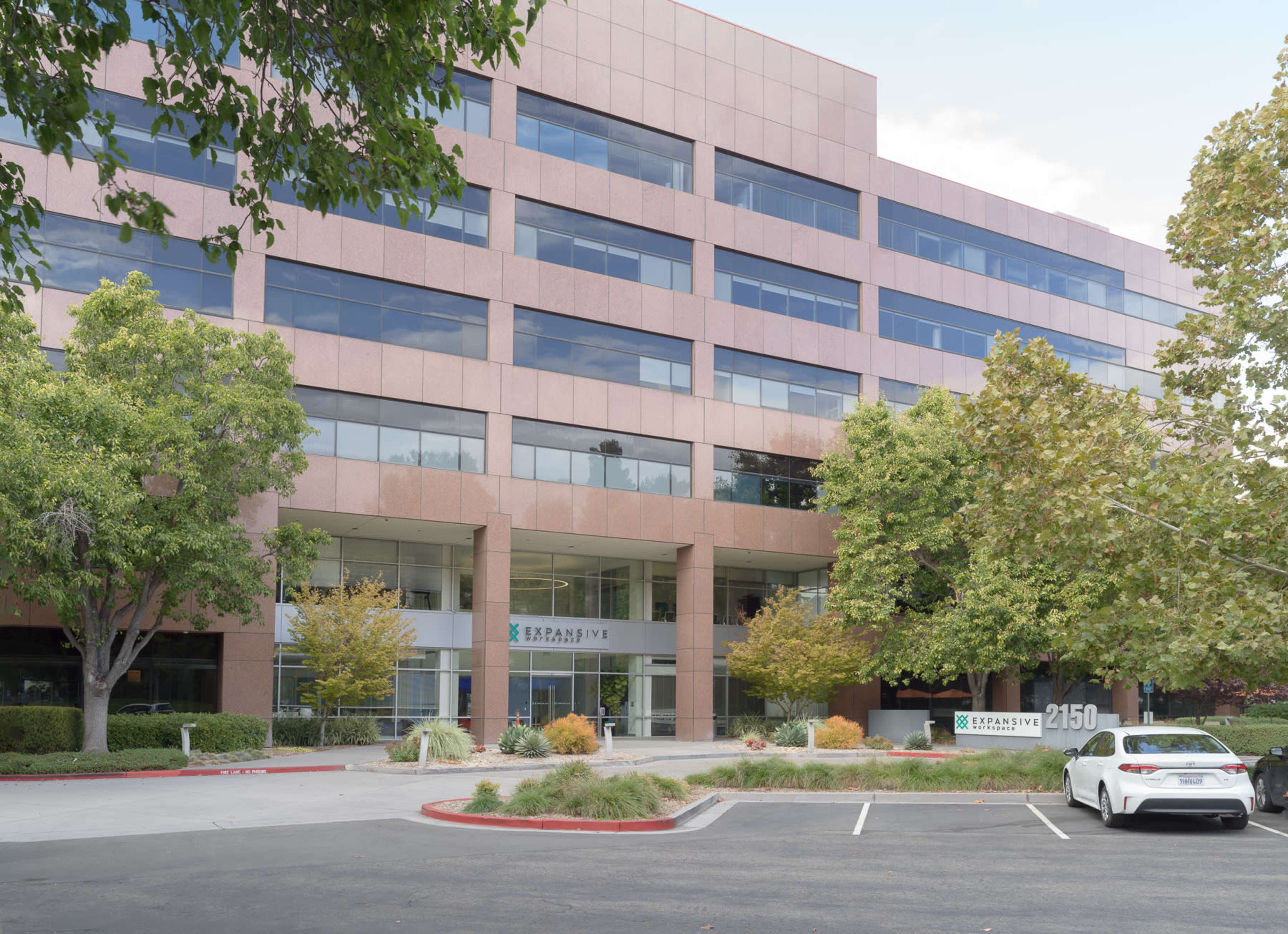 A modern four-story office building with large windows and landscaped greenery is located at 2150.