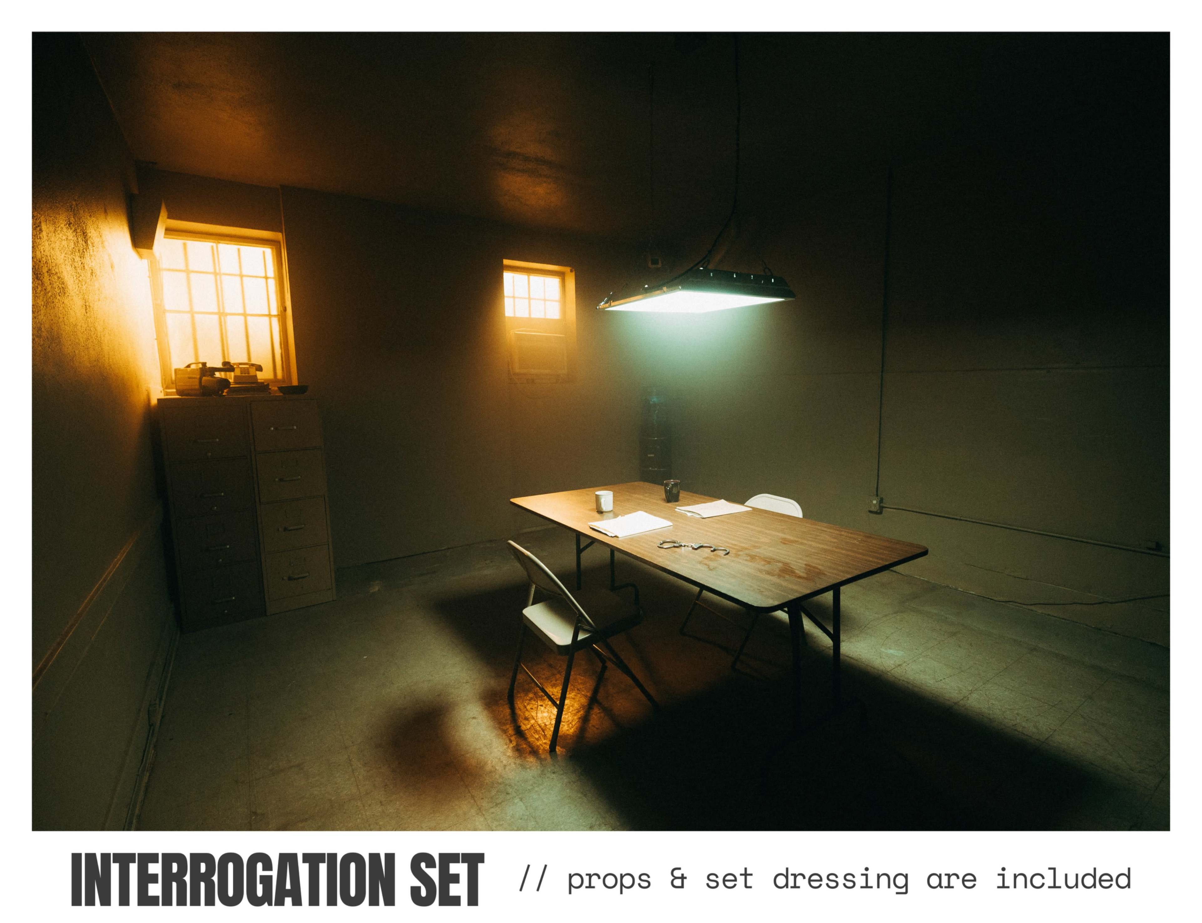 The image shows a dimly lit interrogation room with a wooden table, two chairs, a clipboard, and illuminated by a hanging light fixture.