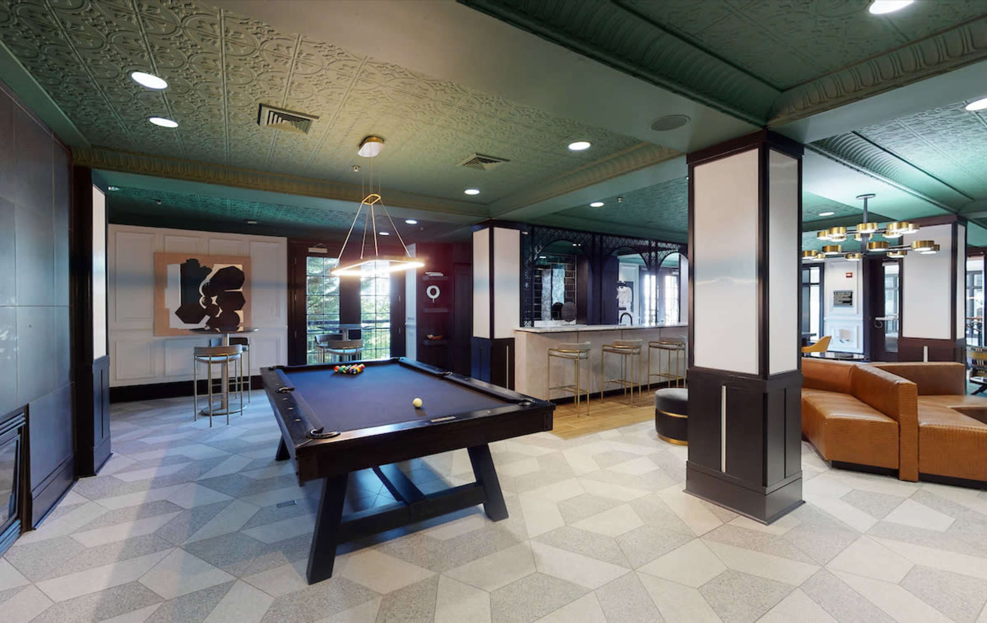 A recreational room featuring a pool table, a bar area with high stools, and a cozy seating arrangement.