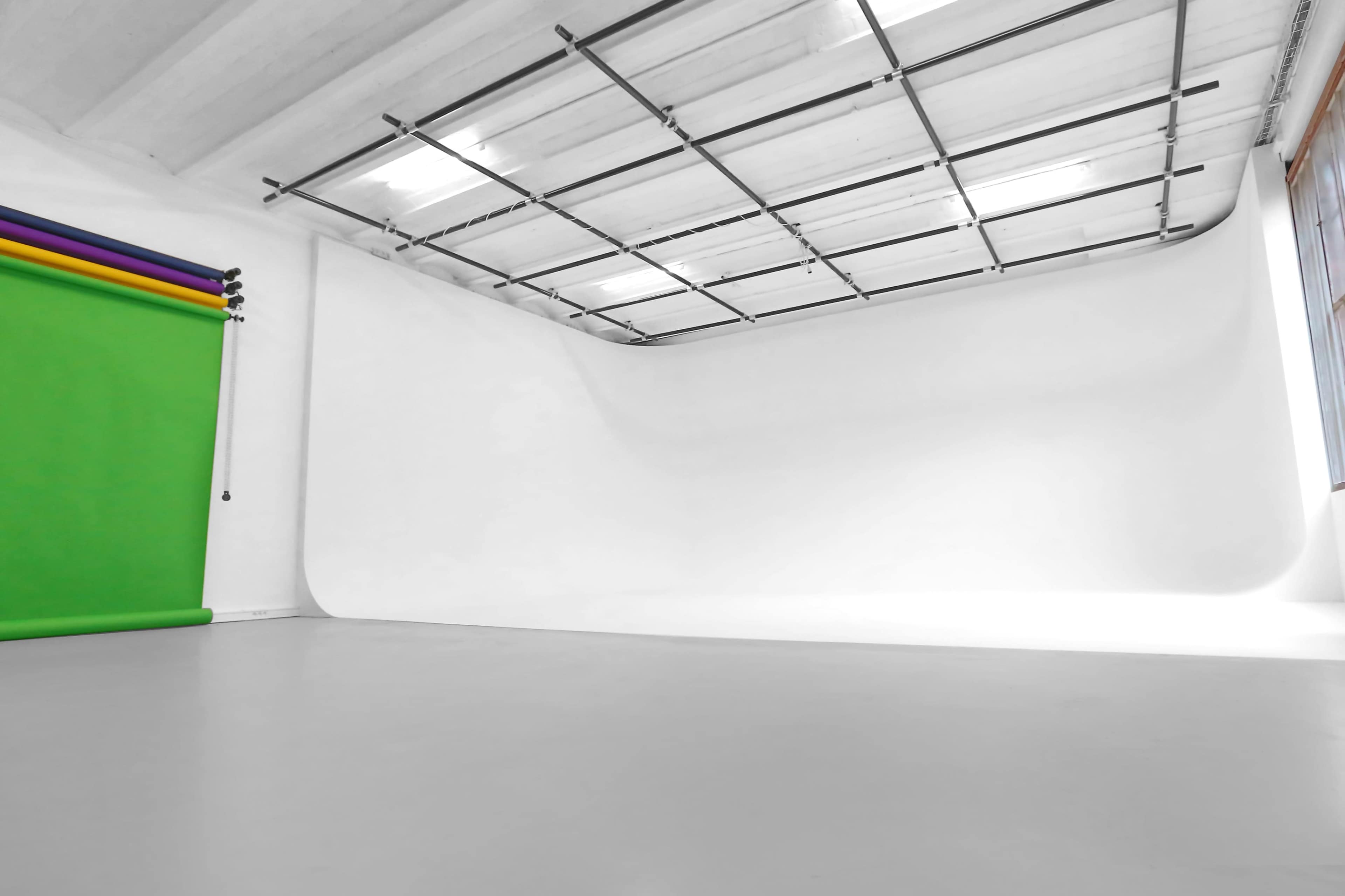 A bright and spacious photography studio with a seamless white backdrop and a green screen.