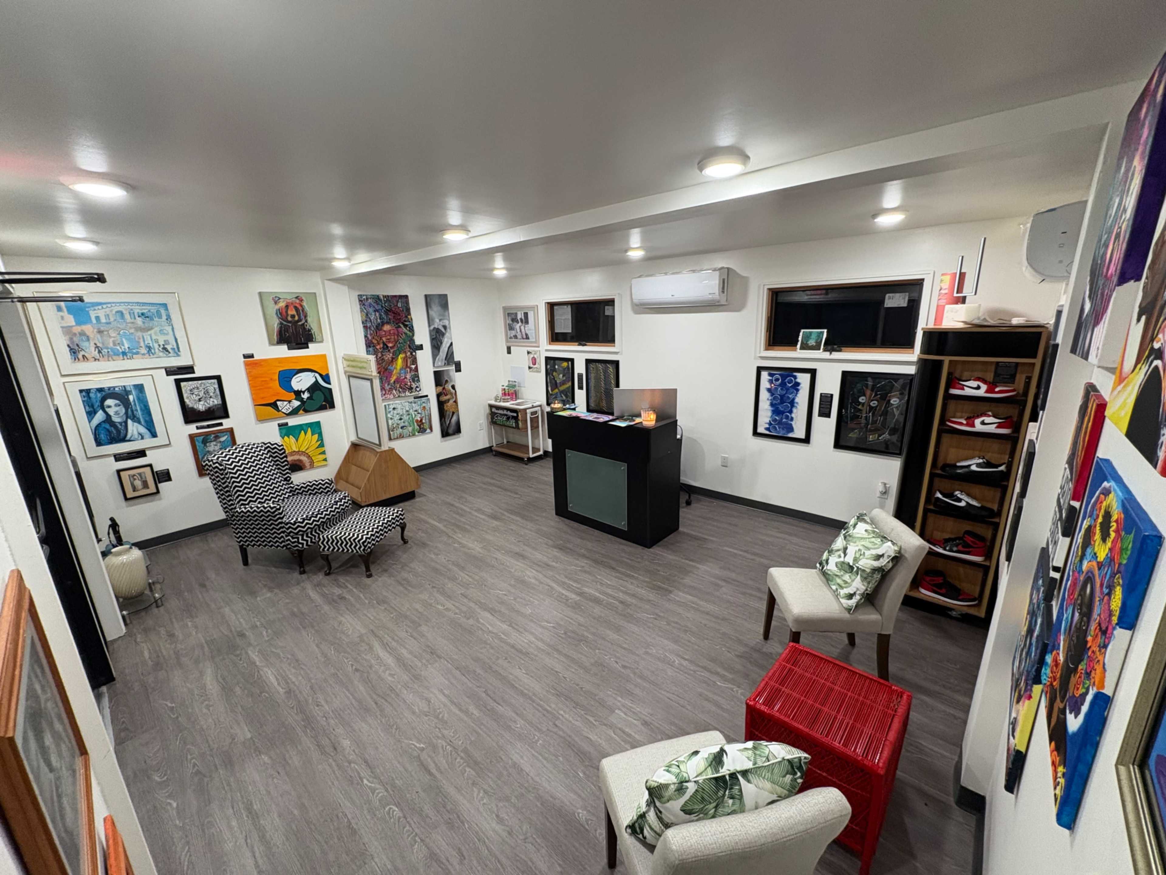 The room features a combination of colorful artwork on the walls, two seating areas, and a small reception desk.