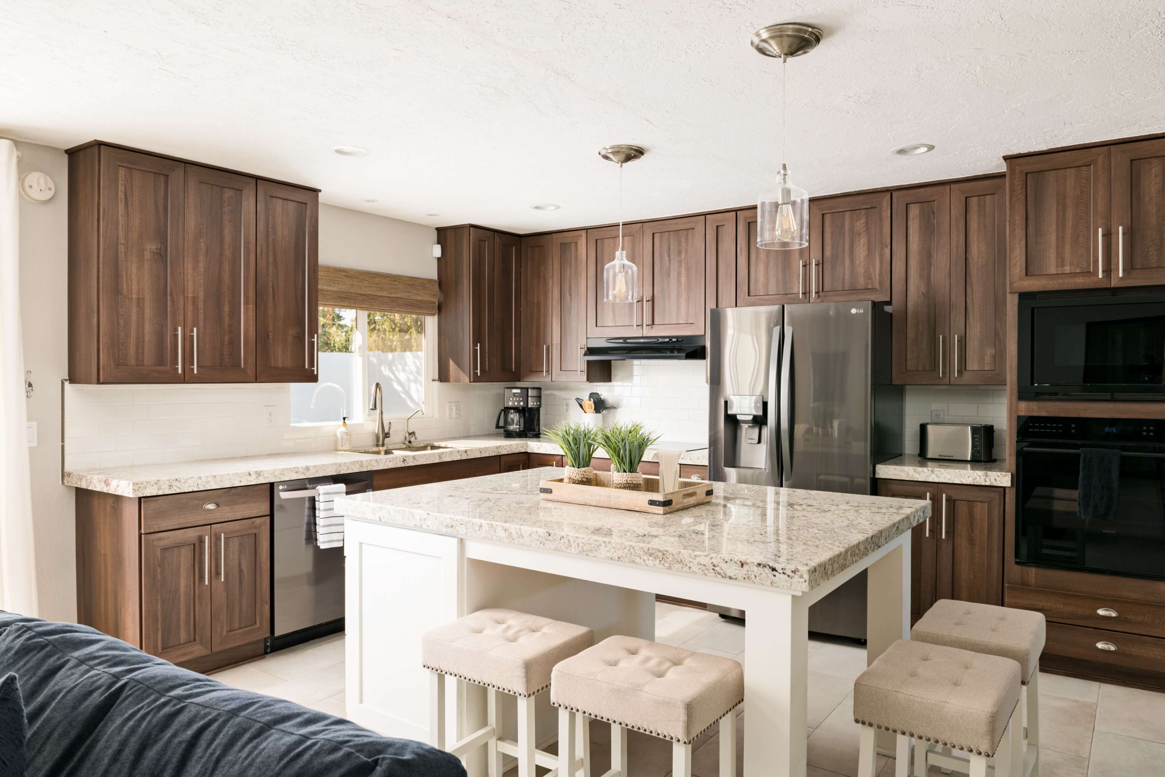 A modern kitchen with dark wooden cabinets, a large island featuring a white countertop, and stainless steel appliances.