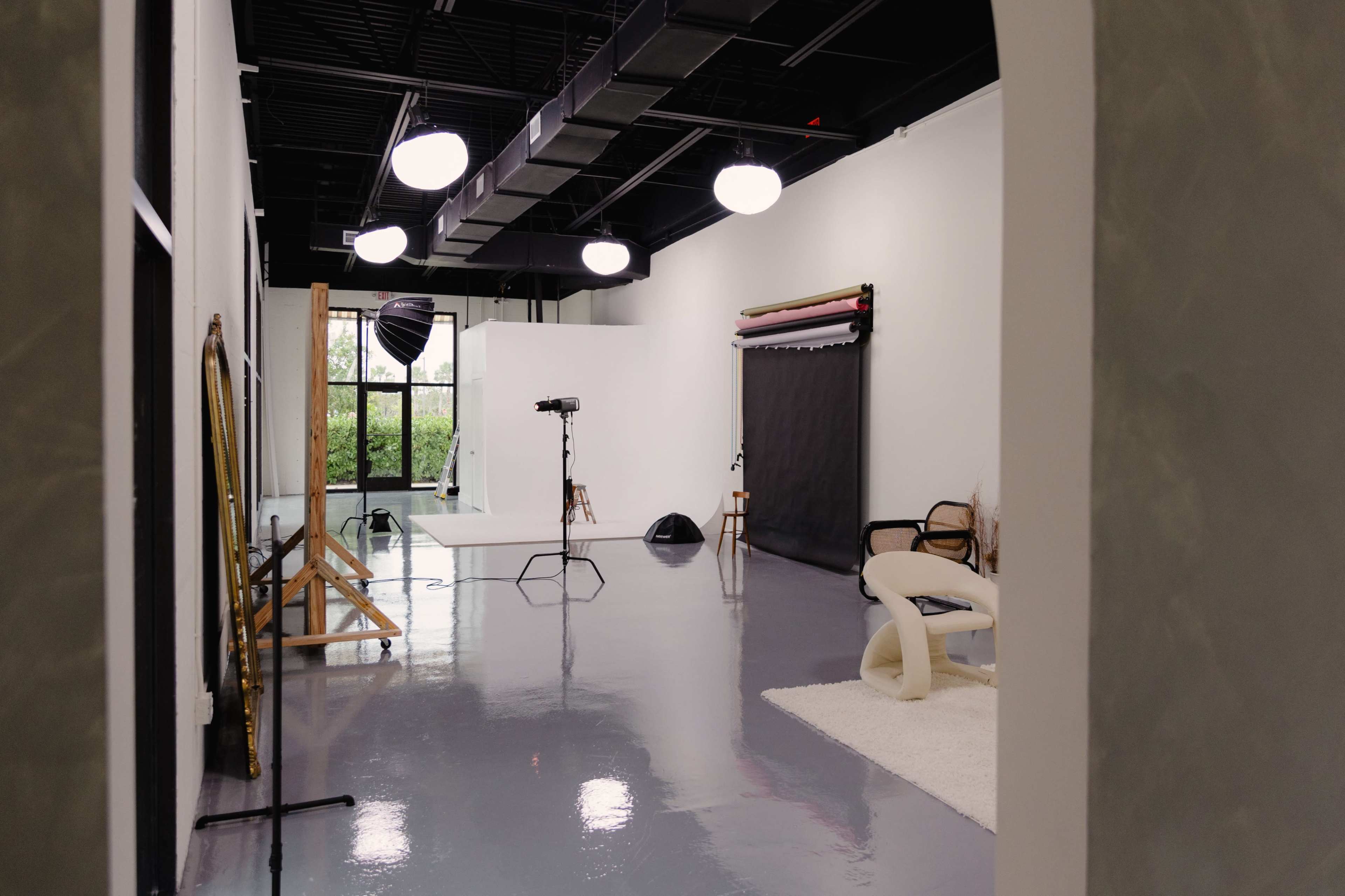 A spacious photography studio features a seamless backdrop, lighting equipment, and various props arranged neatly.