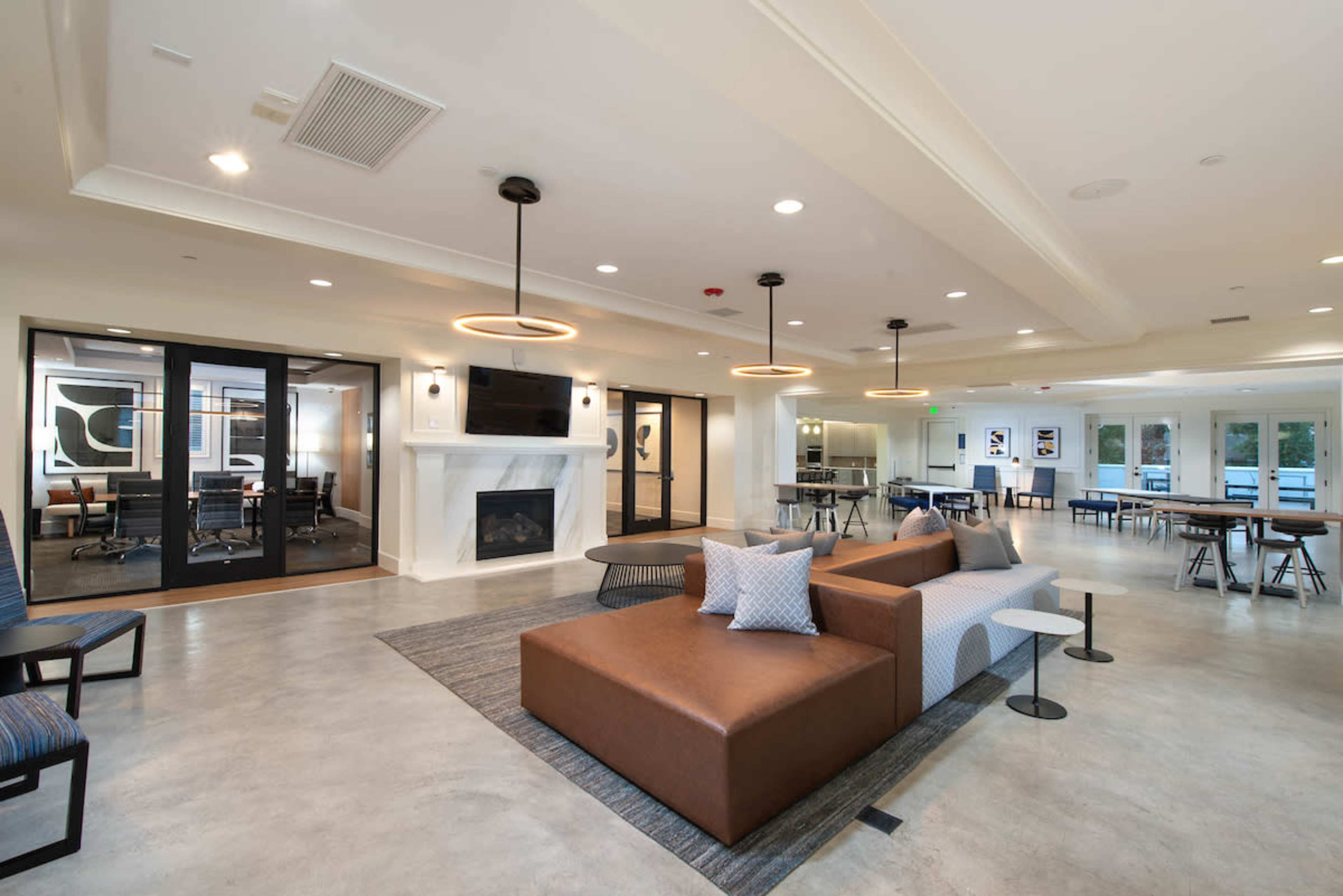 A modern common area with seating, a fireplace, and glass-walled meeting rooms.