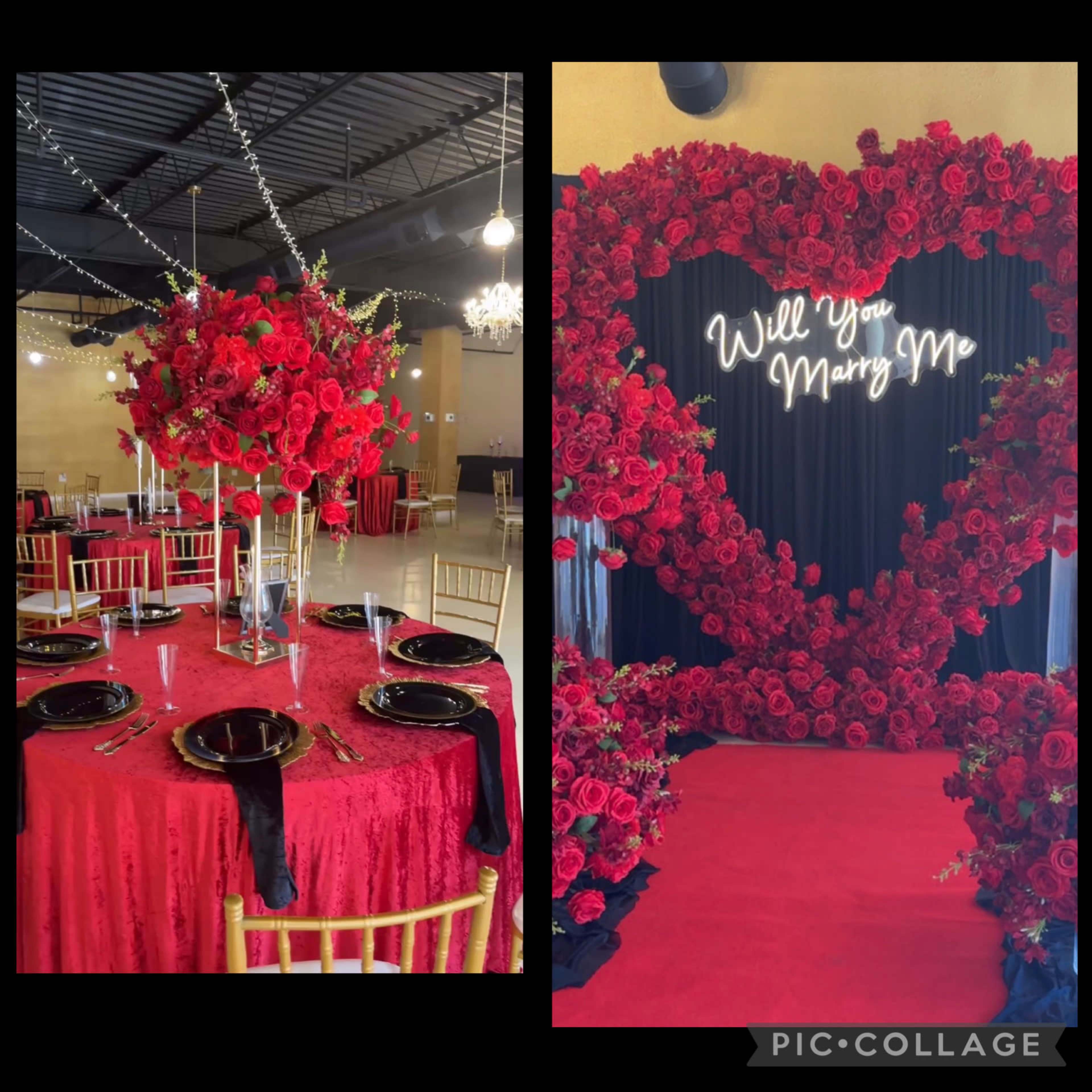 The image shows a decorated event space featuring a table adorned with red roses and a backdrop with the illuminated phrase "Will You Marry Me" surrounded by roses.