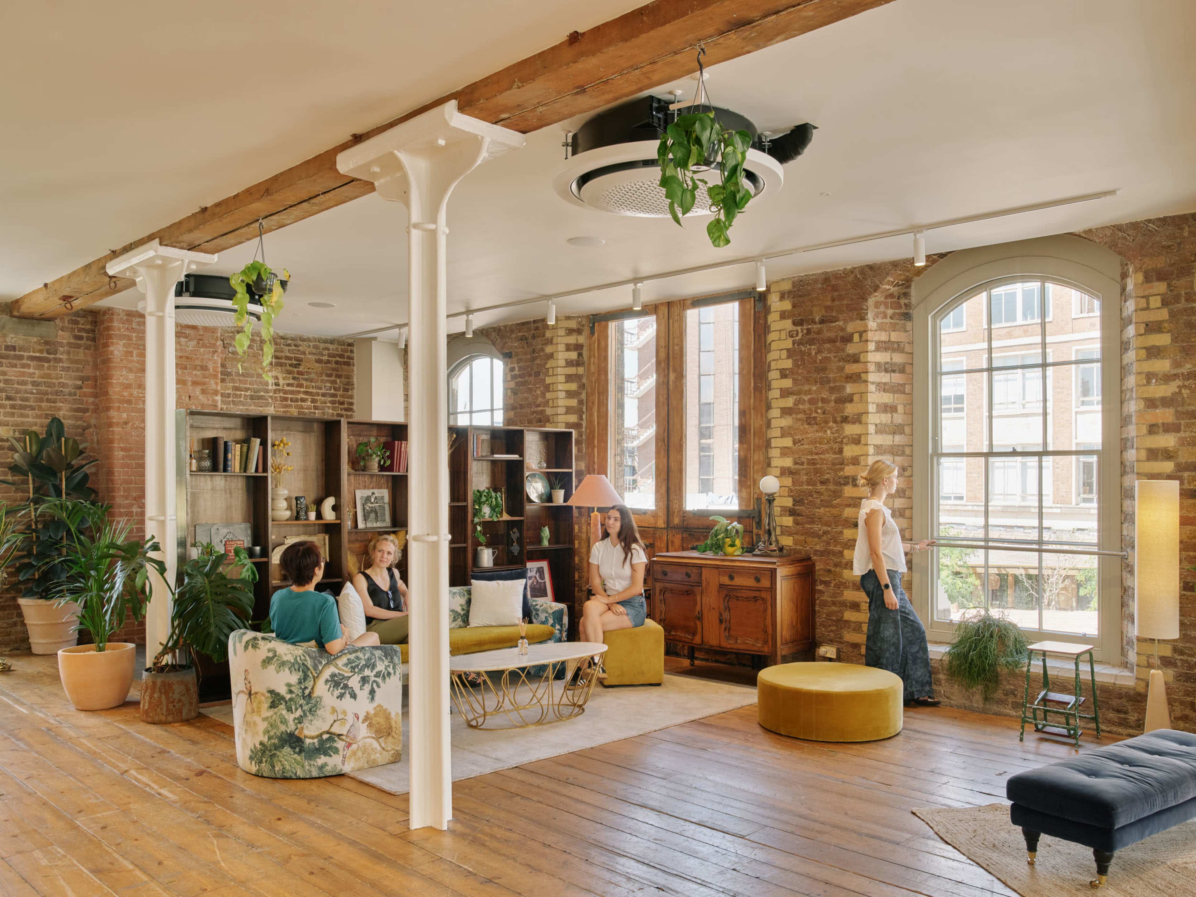 The spacious interior features a mix of seating arrangements, large windows, and plants, creating a comfortable gathering space.