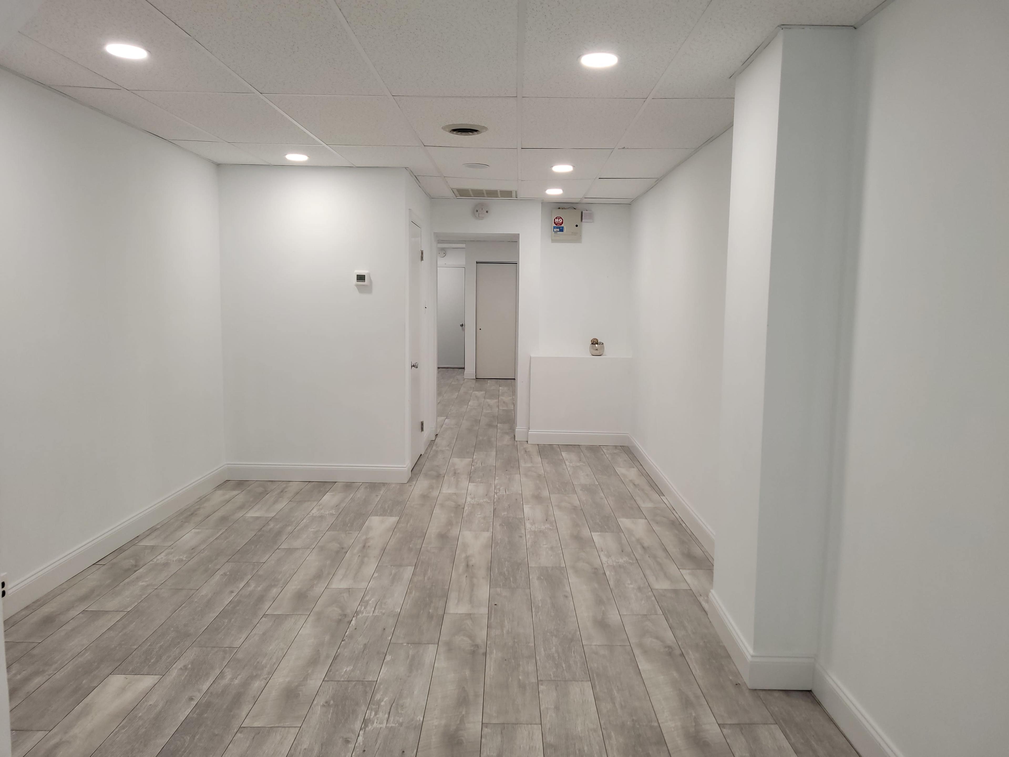 A long, narrow hallway with light-colored walls and tiled flooring.