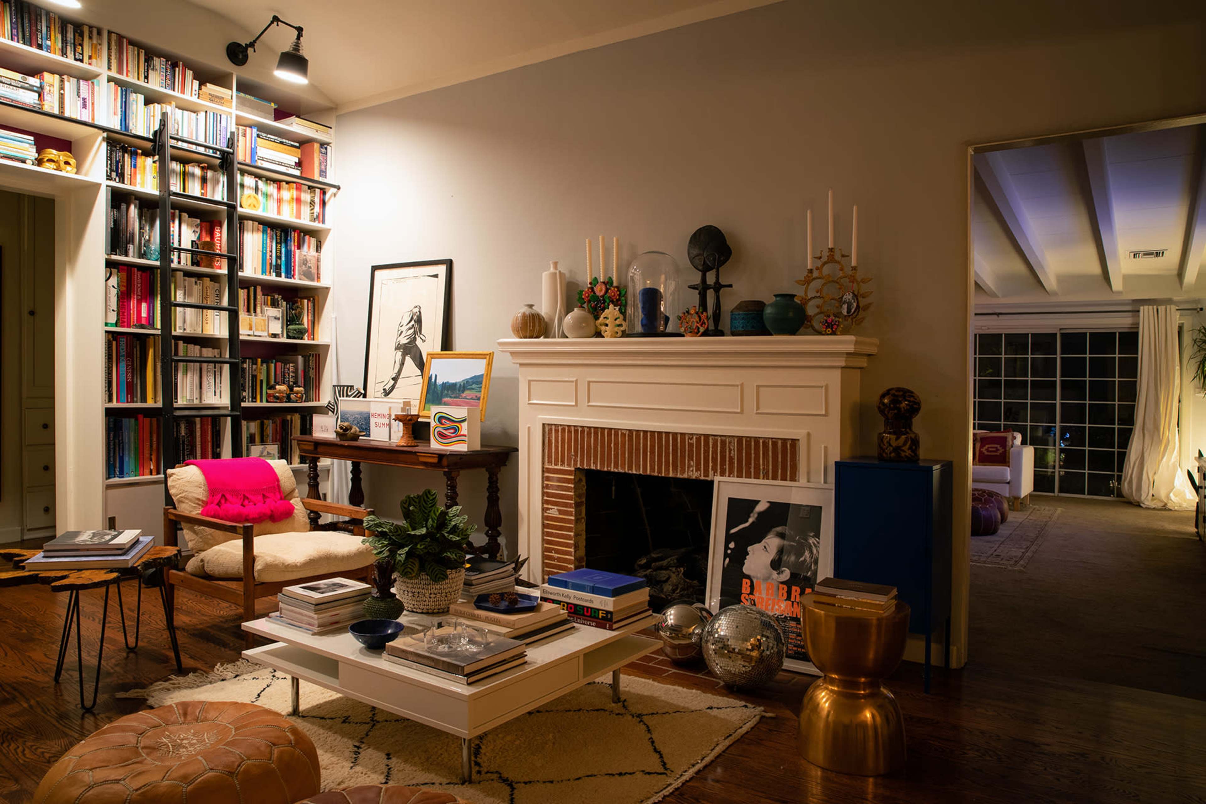 A cozy living room with a fireplace, surrounded by a built-in bookshelf filled with books, a coffee table in the center, and various decorative items.