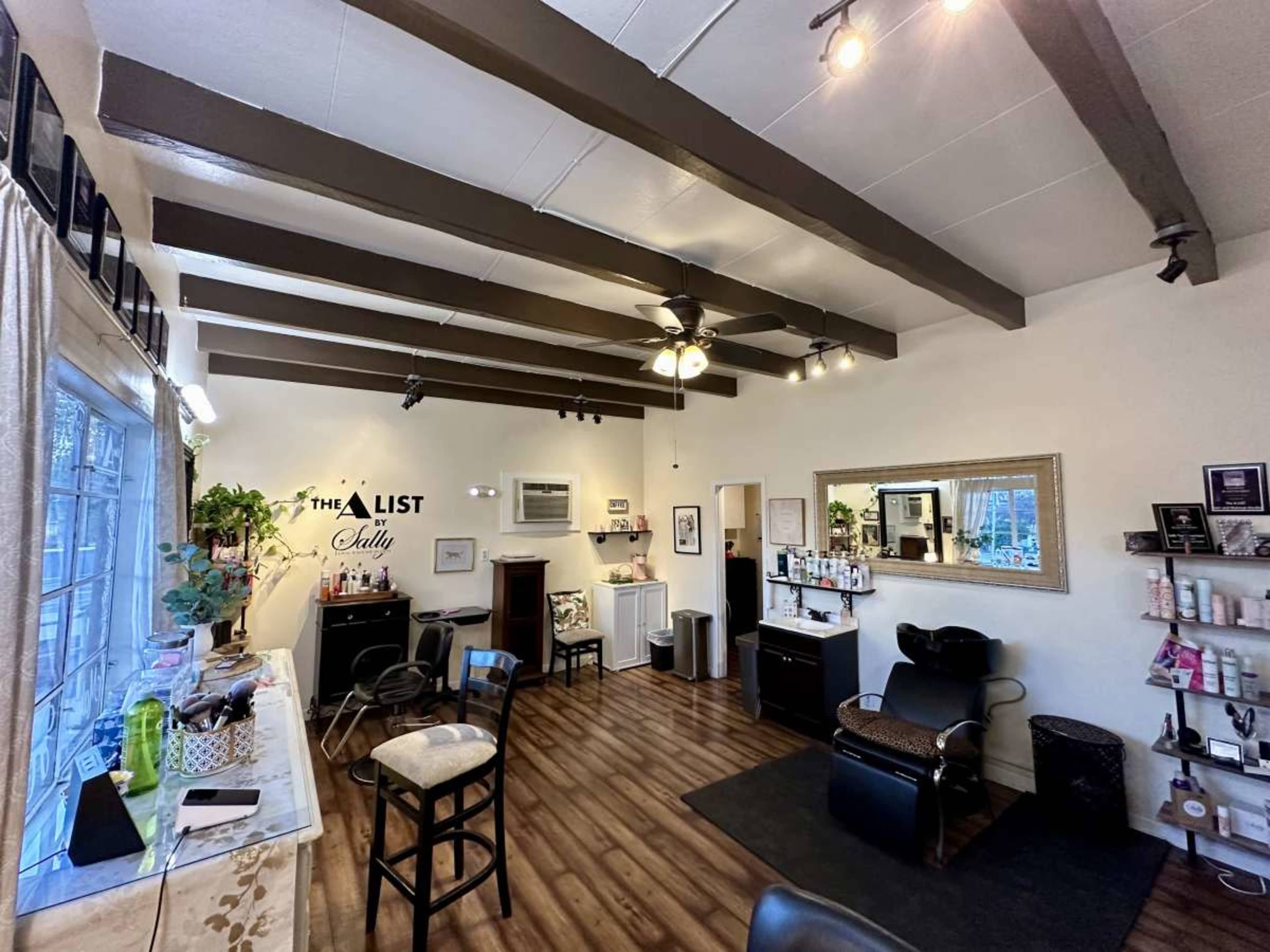 The interior of a salon with wooden beams, stylized furniture, hair care products on shelves, and a mirror reflecting the space.