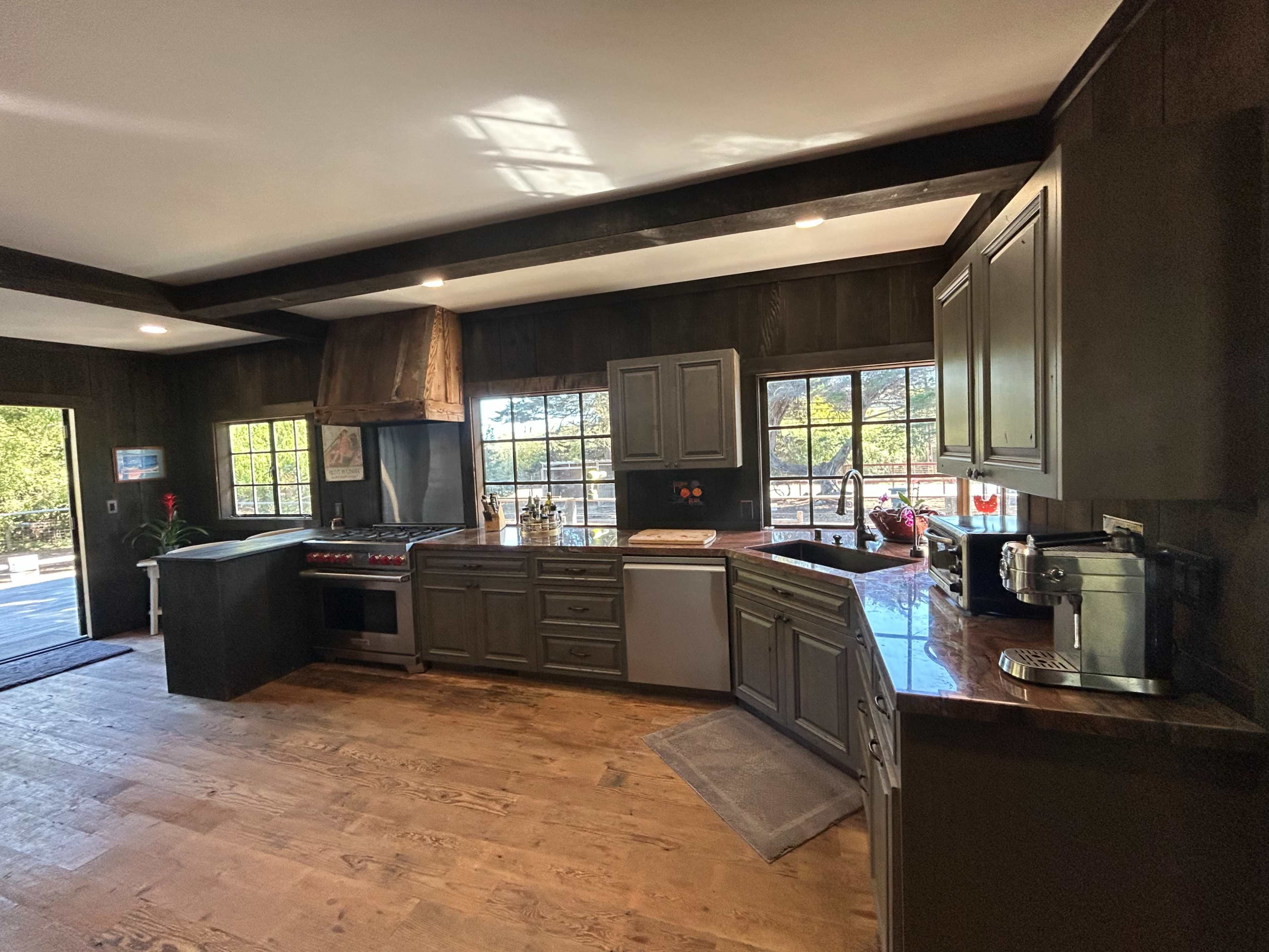The kitchen features dark wood cabinetry, a large window allowing natural light, and modern appliances, including a stovetop and dishwasher.