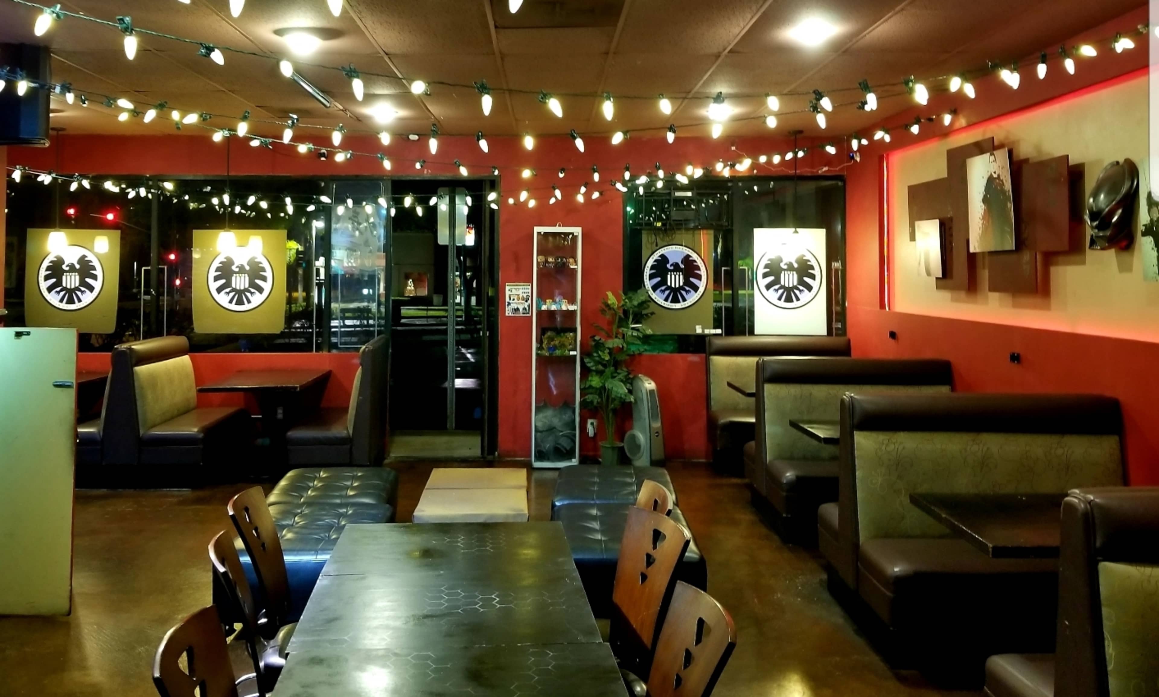 The interior of a restaurant features booths, tables, and wall decor, illuminated by string lights hanging from the ceiling.