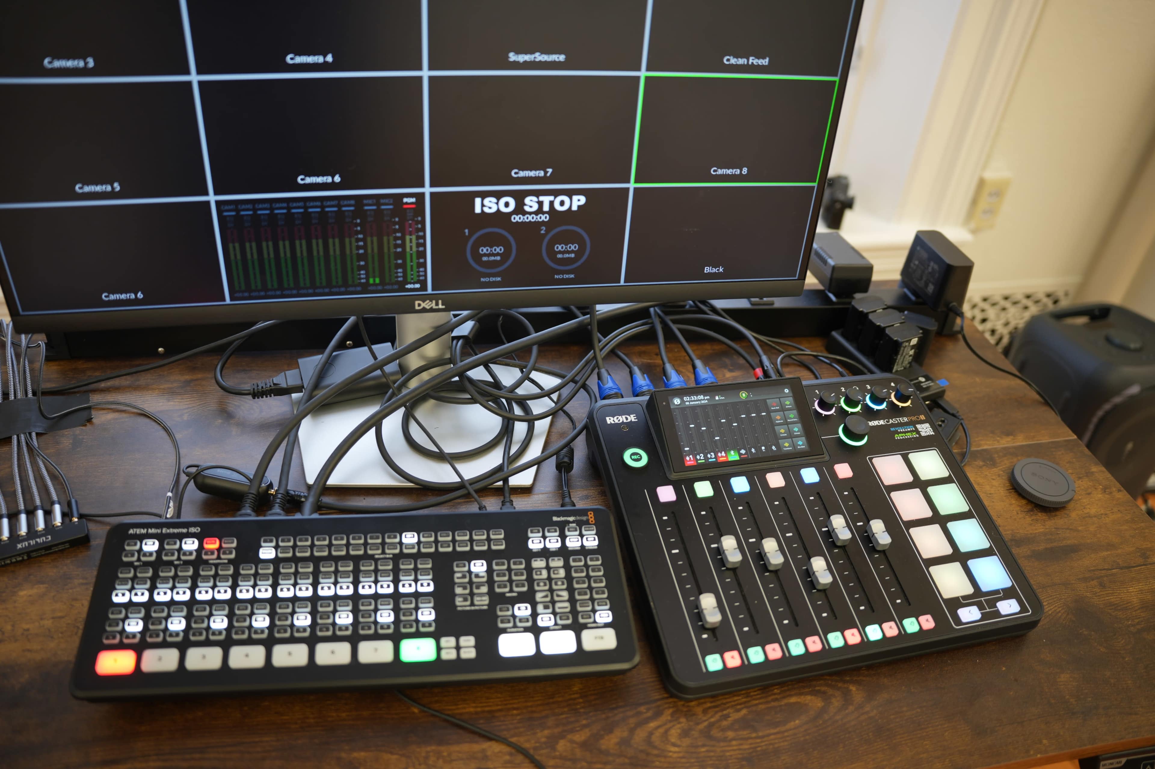 A control panel with various faders, buttons, and a keyboard, connected to a monitor displaying a grid layout for camera inputs and settings.