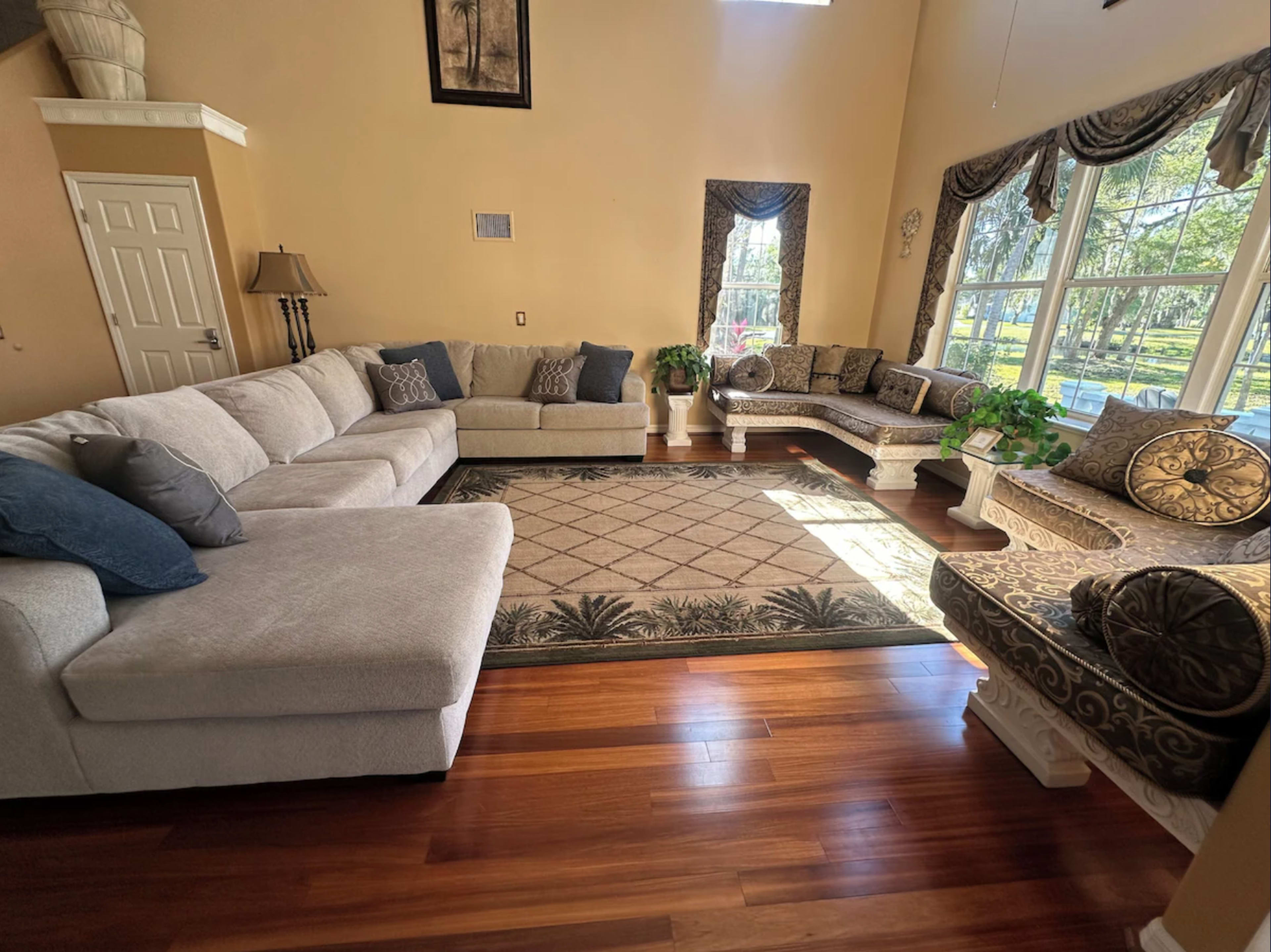 A spacious living room with a large sectional sofa, decorative seating, and large windows allowing natural light to fill the space.