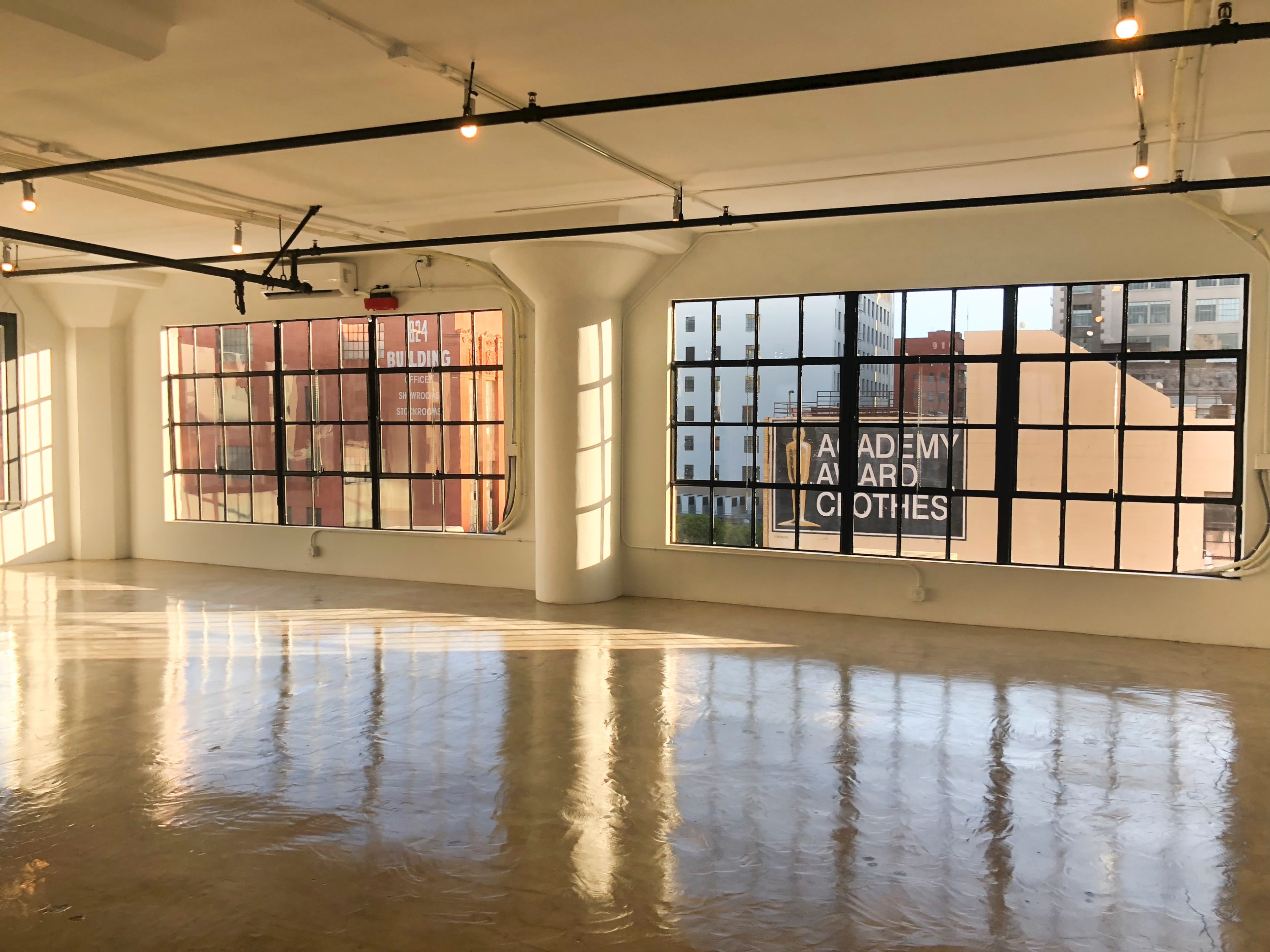 The image shows an industrial-style room with large windows allowing natural light to illuminate the polished concrete floor.
