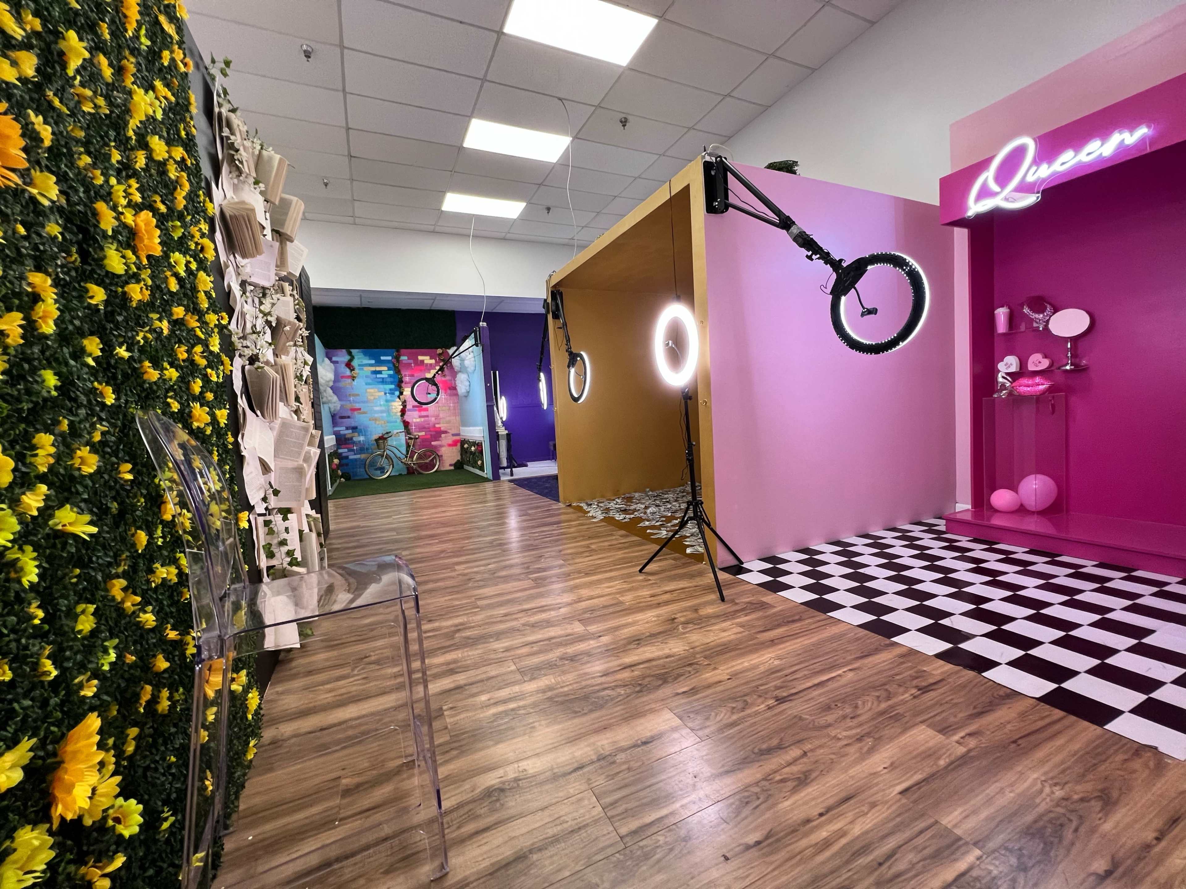 A vibrant studio space featuring colorful walls, decorative elements, and professional lighting equipment, including a ring light and a chair for photo sessions.