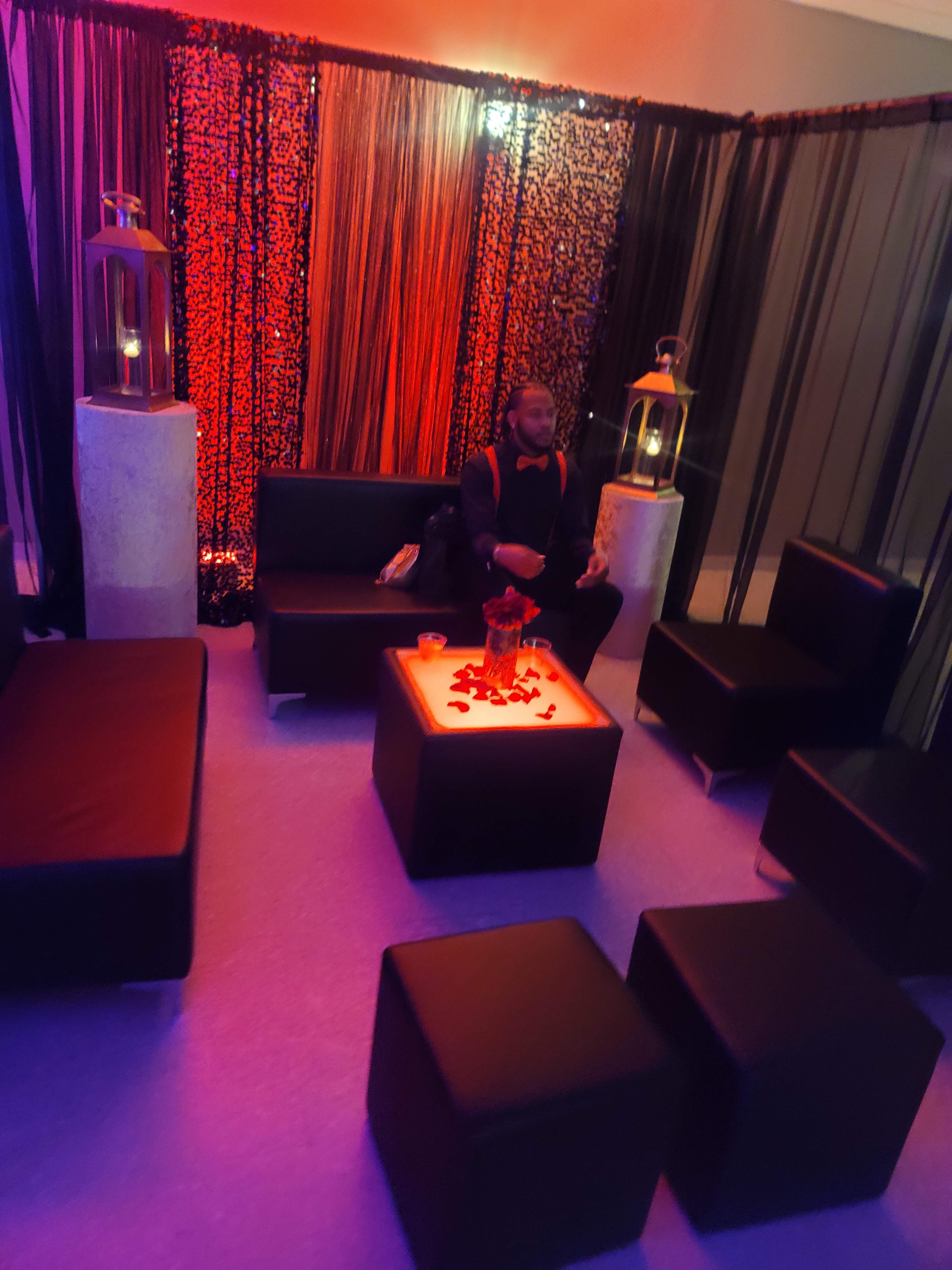 The scene features dimly lit seating with black furniture and decorative lanterns, creating a cozy atmosphere.