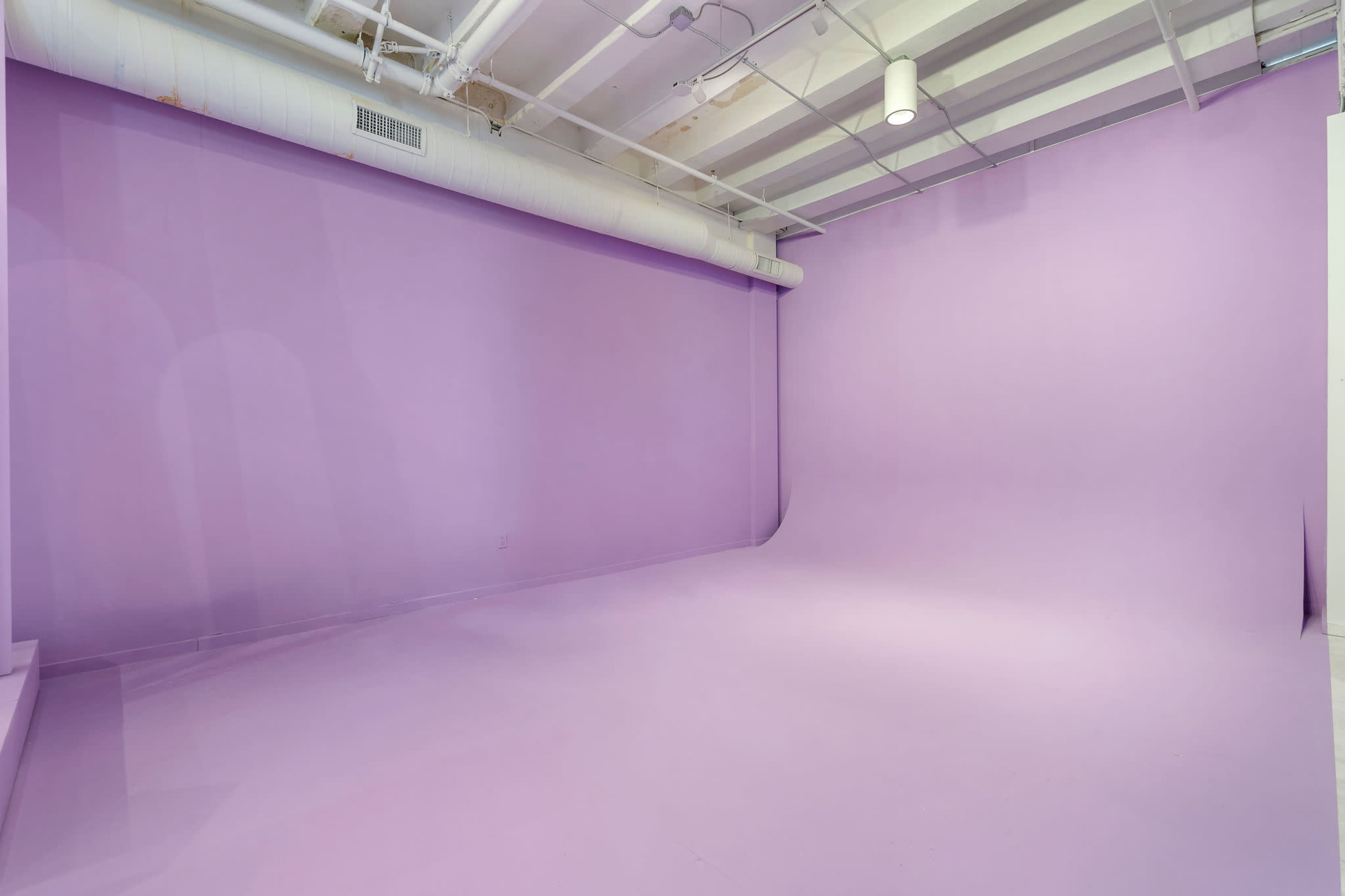 A studio space with smooth, purple walls and floor, designed for photography or filming.