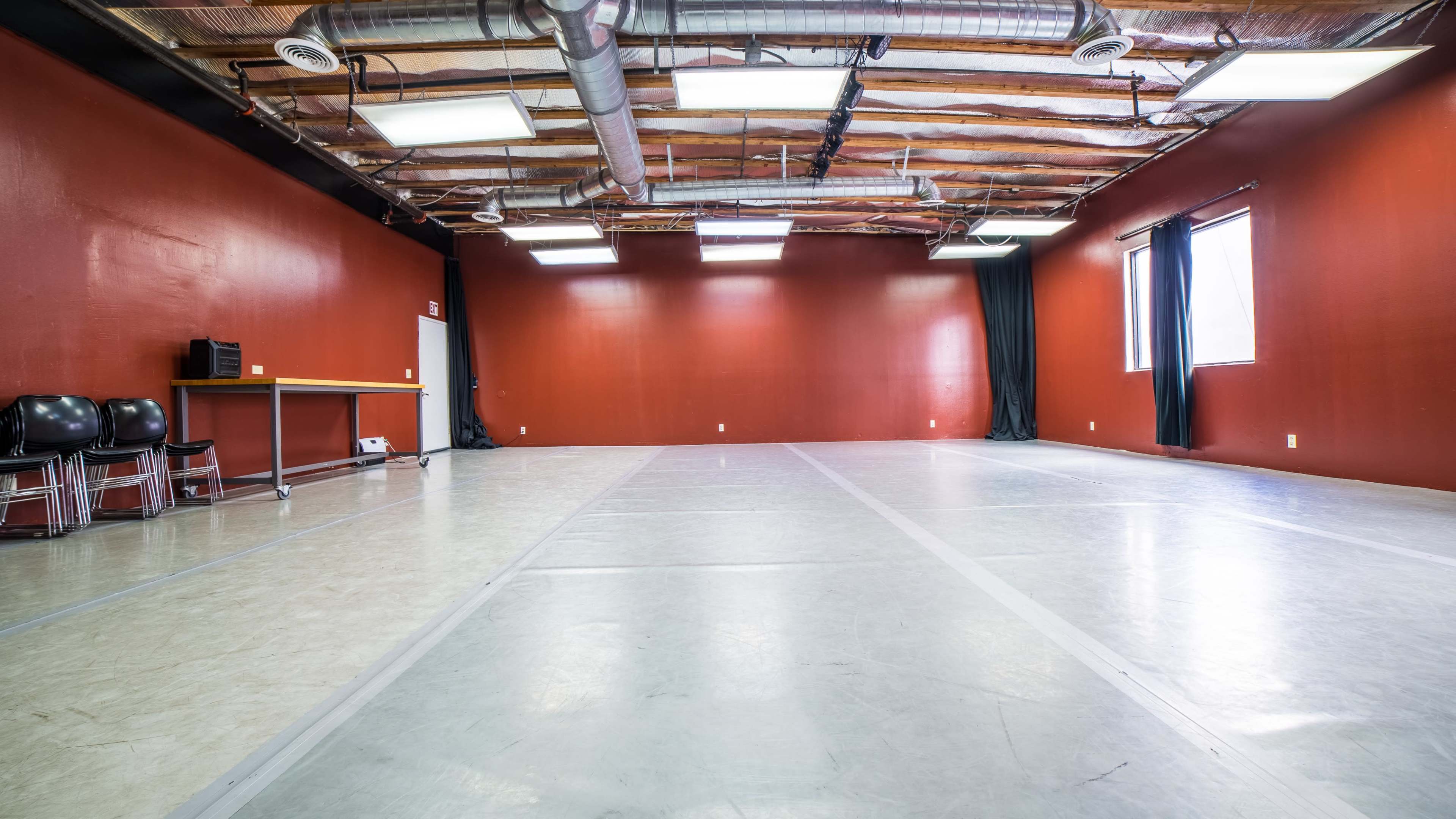 An empty studio space with red walls, a smooth floor, and overhead lighting.