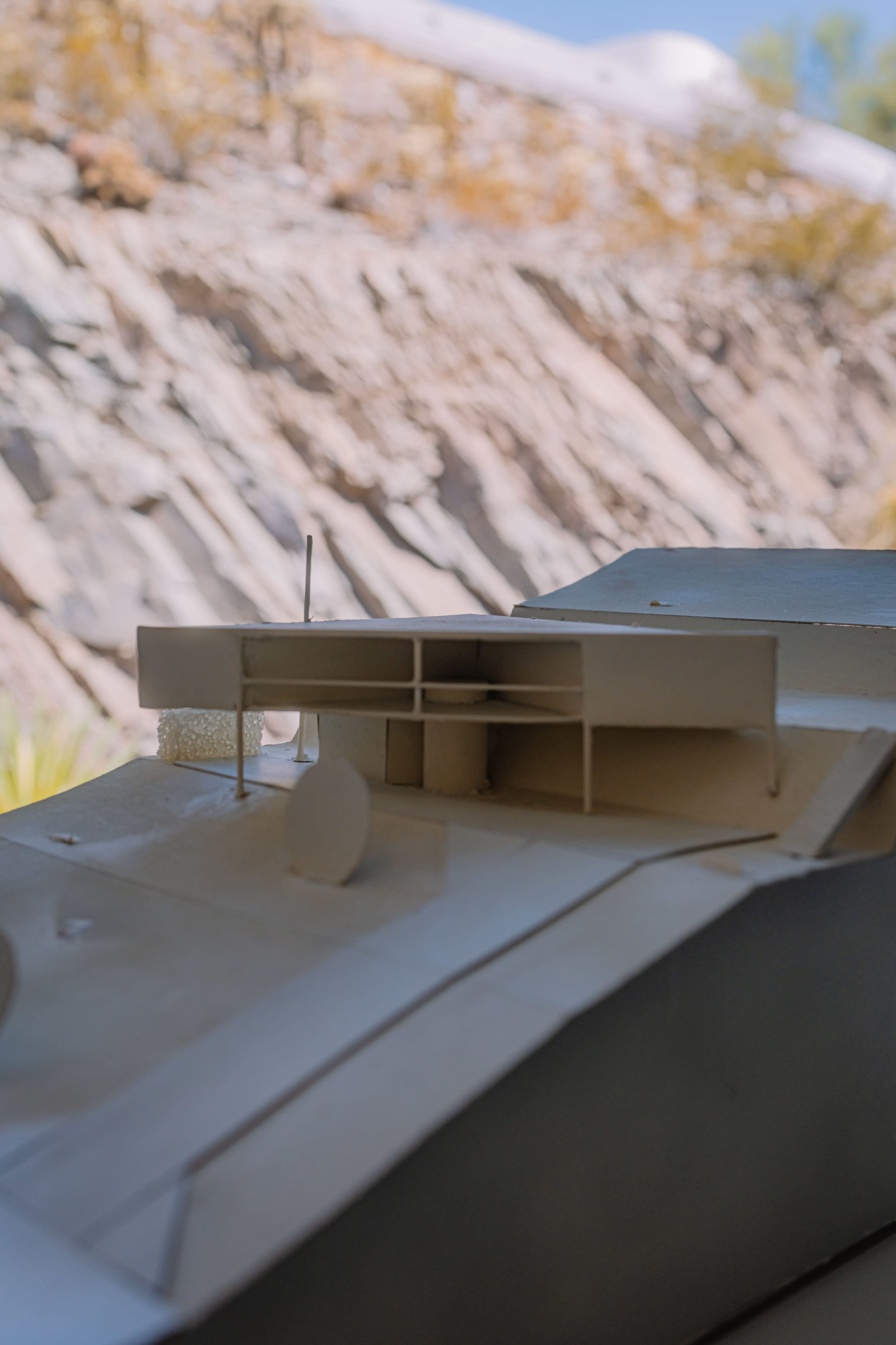 The image shows a close-up of a model vehicle with a flat-topped design, mounted on a rocky terrain.