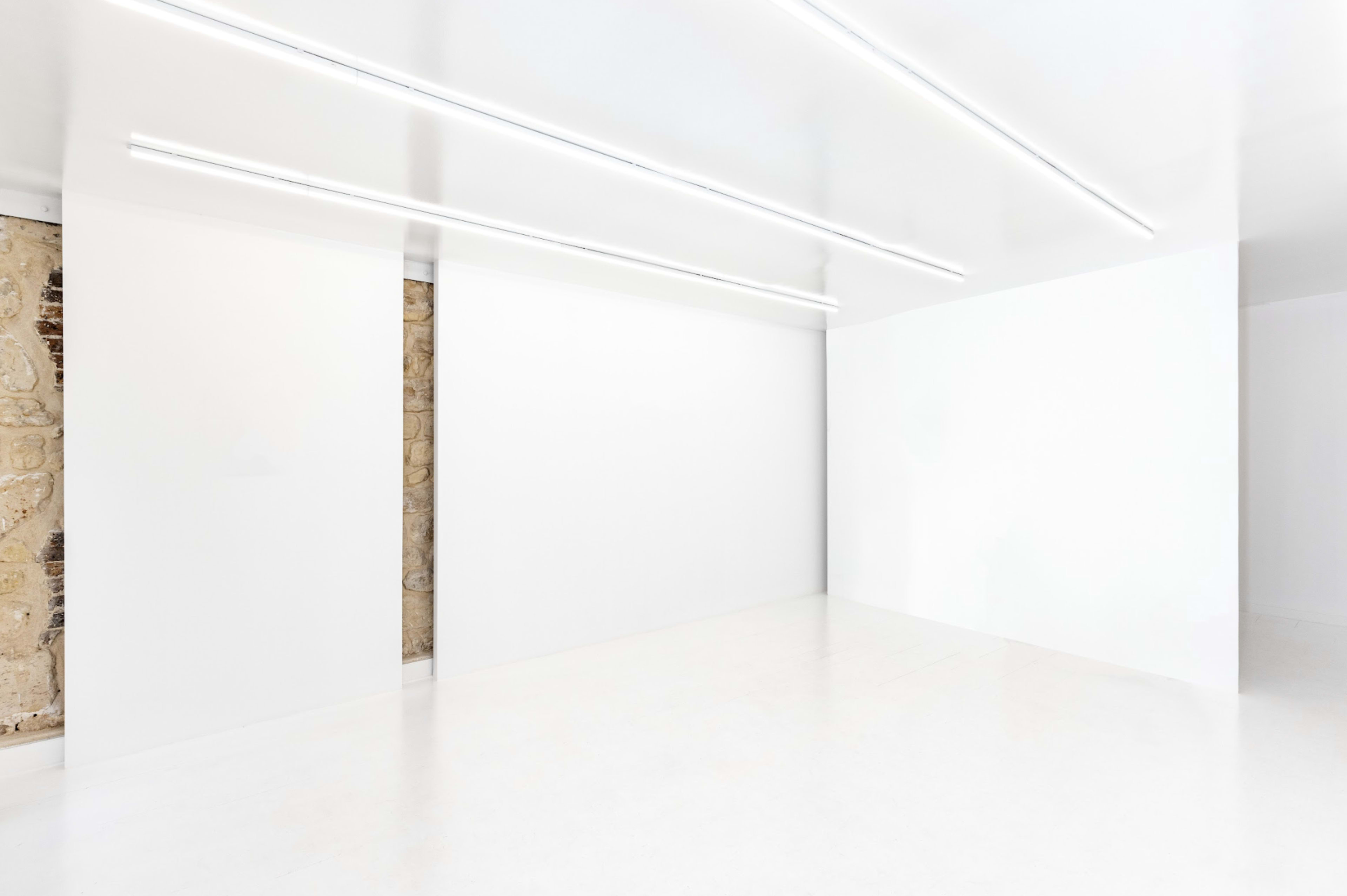 The image shows a minimalist interior space with white walls and bright overhead lighting.
