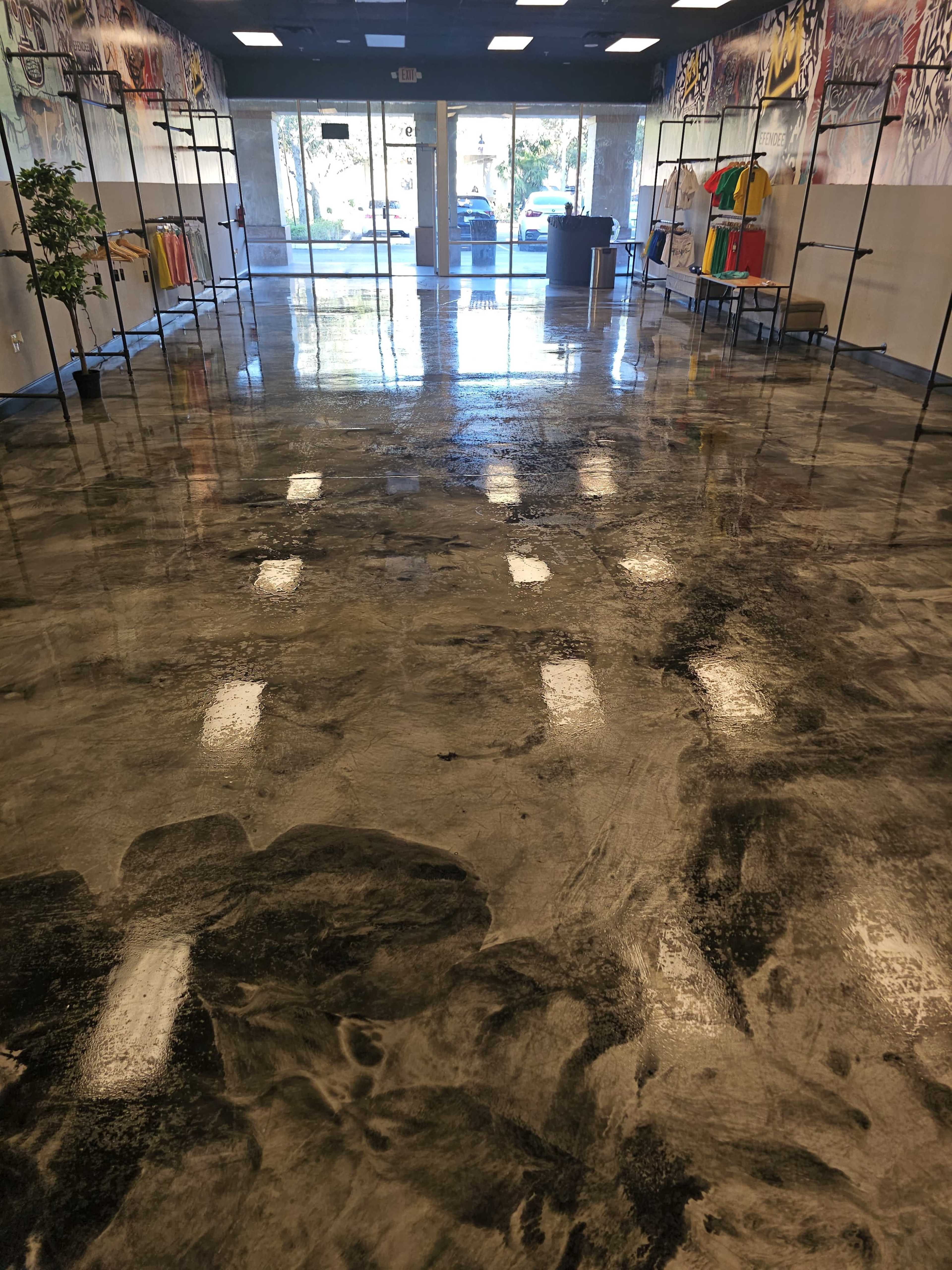 The image shows a spacious retail store interior with a polished, reflective floor and clothing racks along the sides.