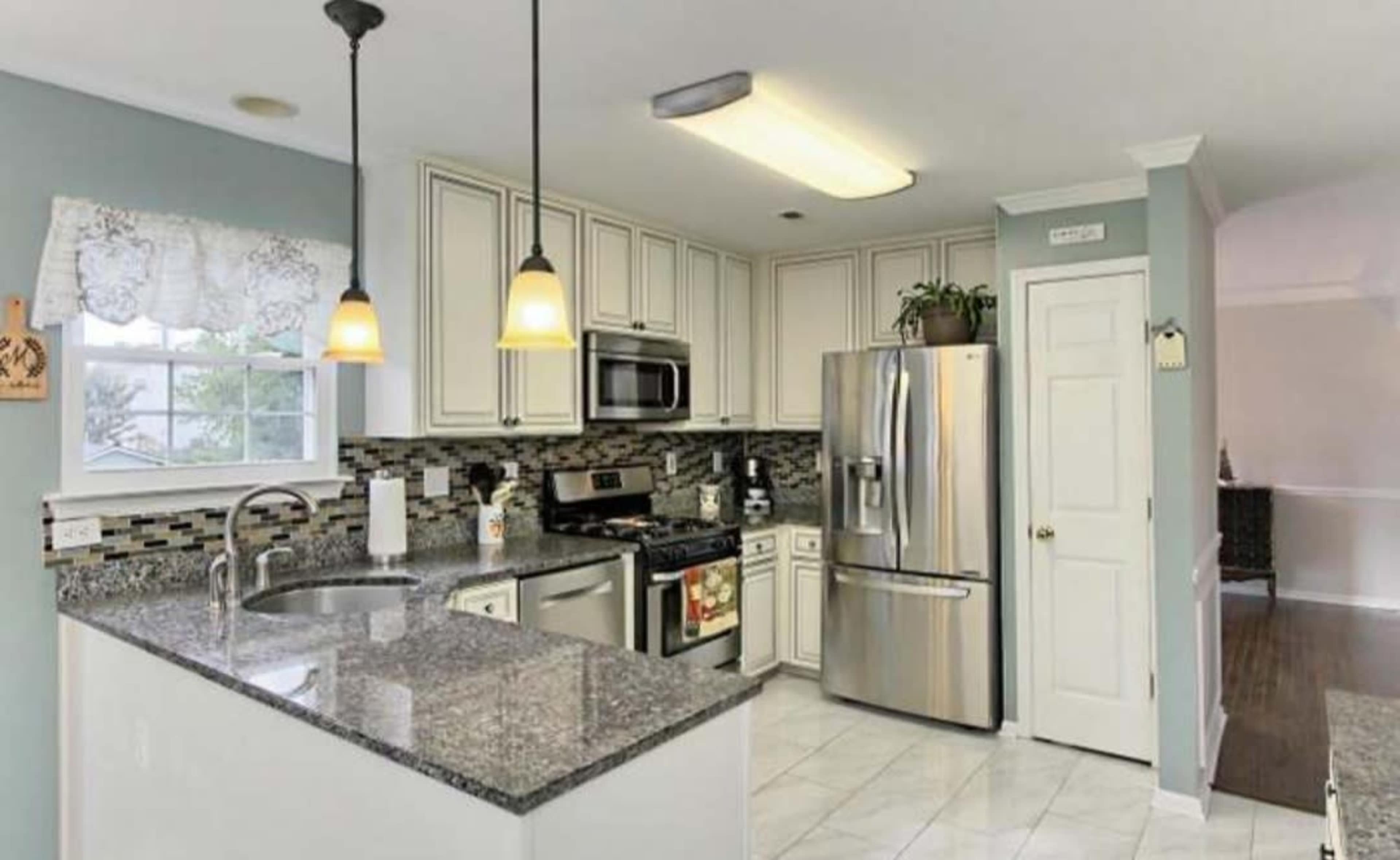 A kitchen with white cabinets, stainless steel appliances, and dark granite countertops.