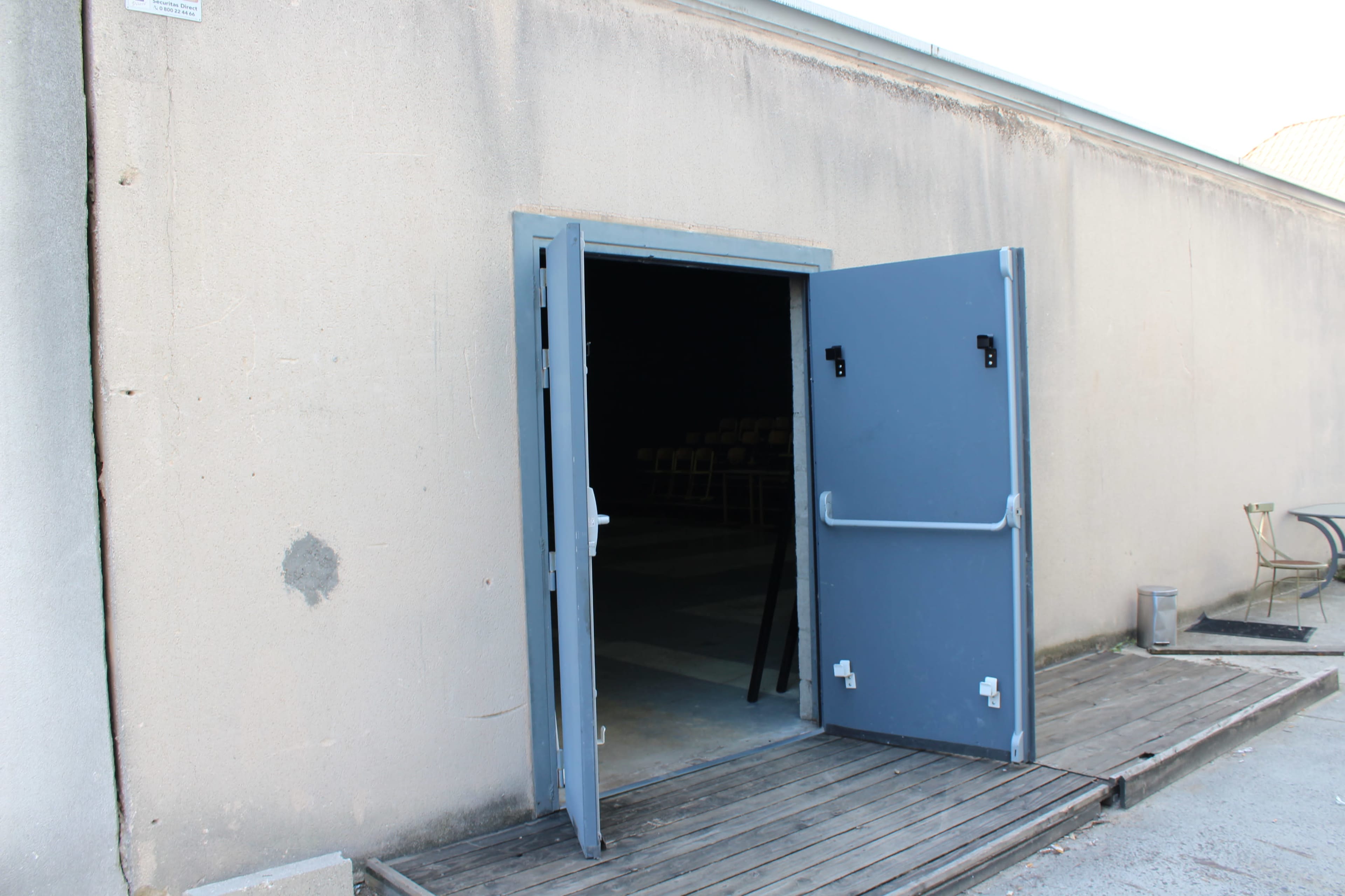 An open double door reveals a dark interior space with visible seating.