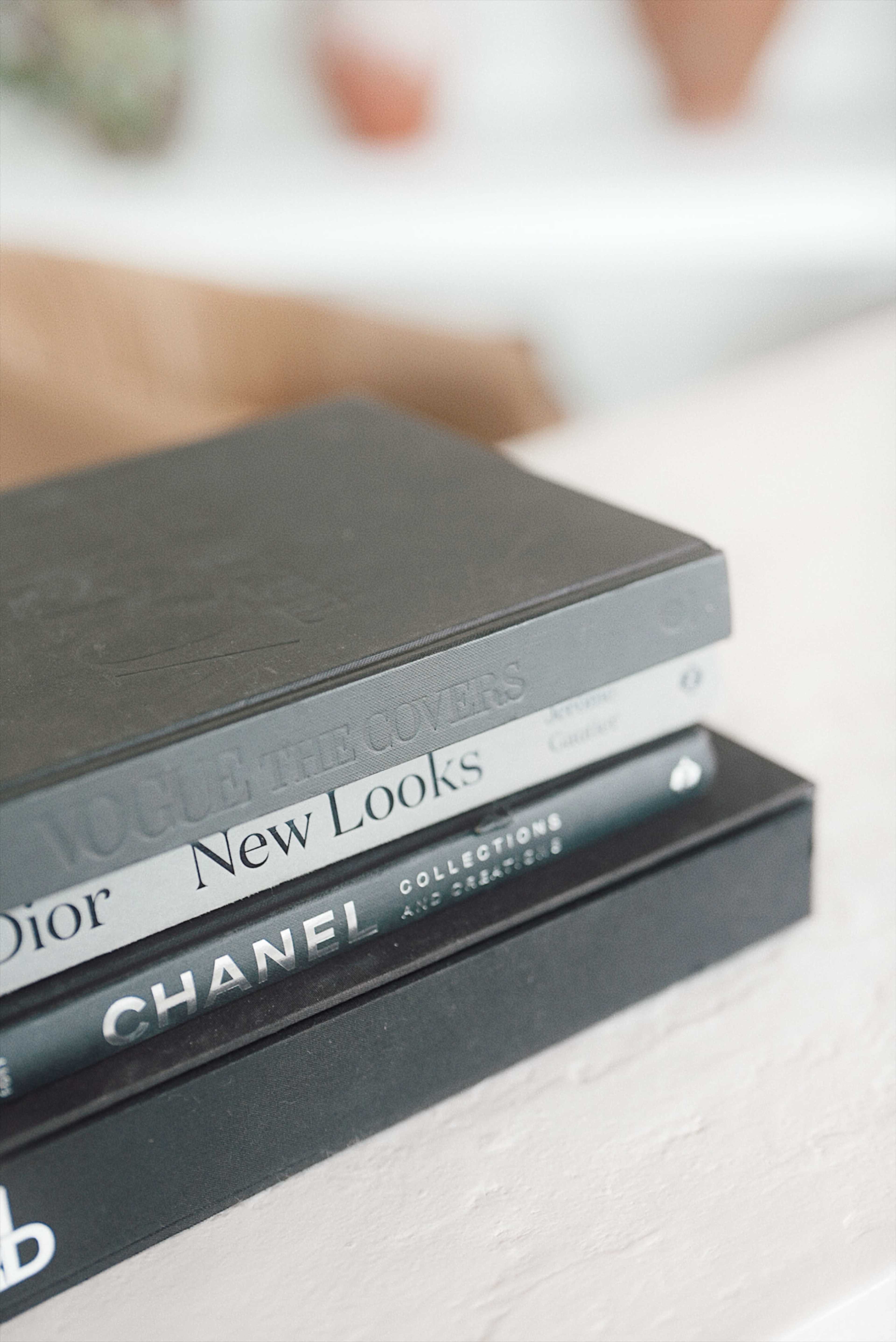 The image shows a stack of three books with covers featuring titles related to fashion, resting on a light-colored surface.